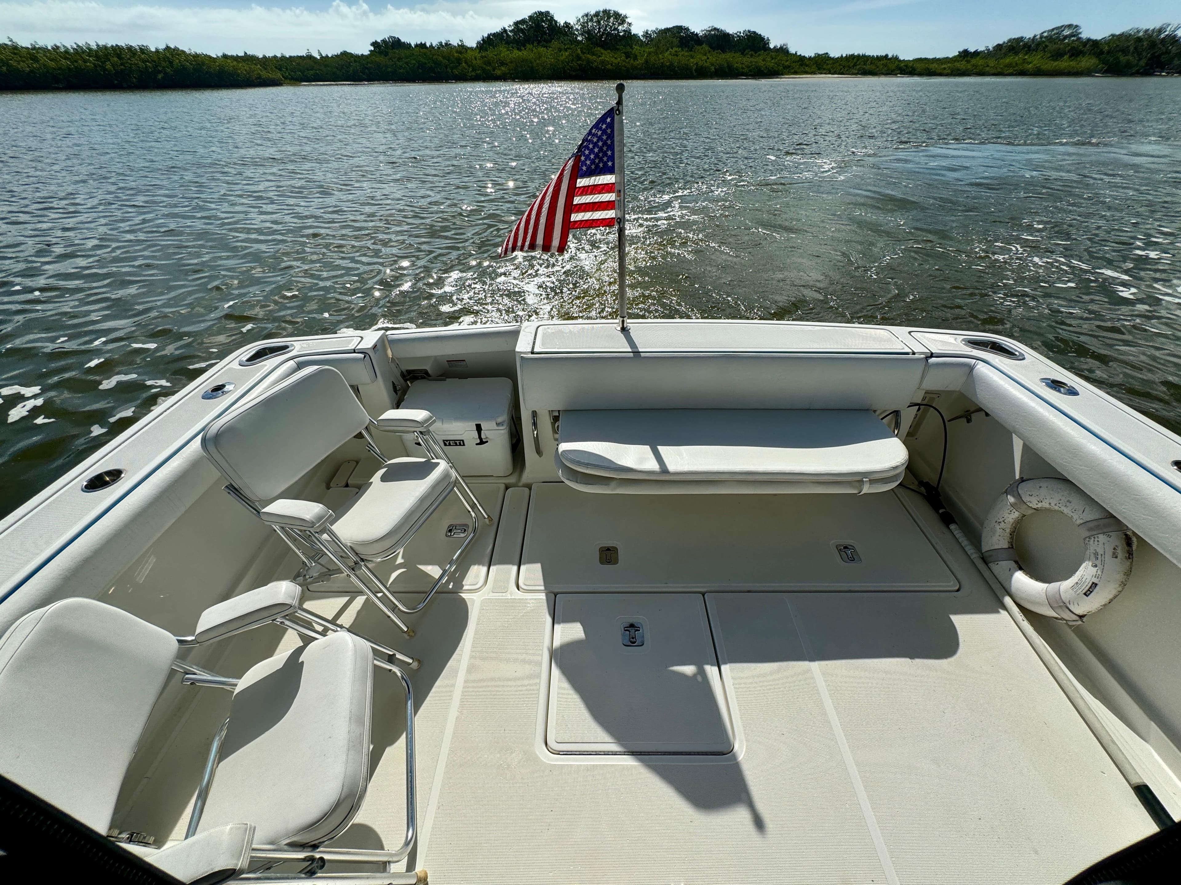 2006 Tiara Yachts 3200 Open boat deck with chairs and American flag on water.