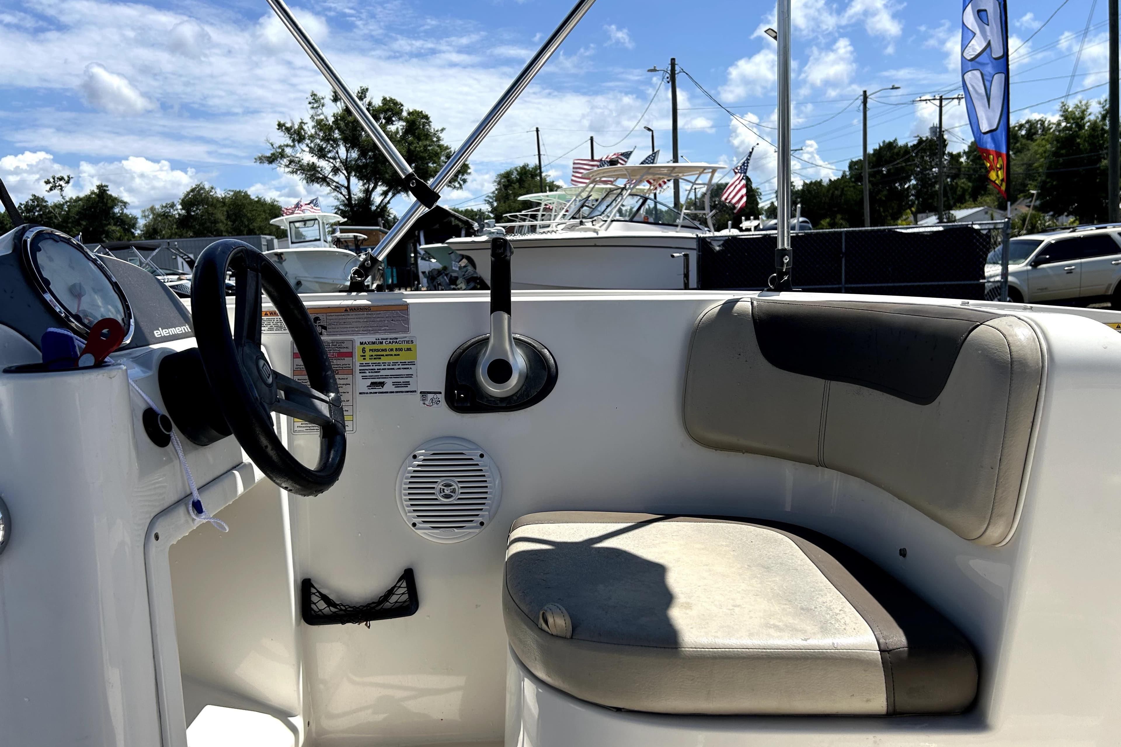 2017 Bayliner Element E16 boat interior with steering wheel and seating under a sunny sky.
