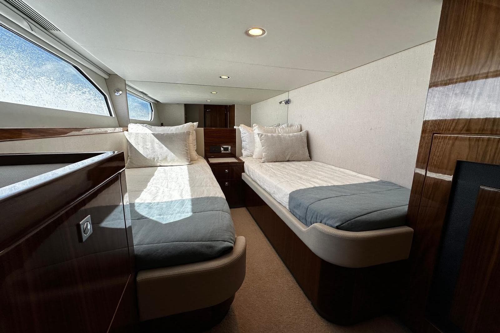 Luxurious interior of 2023 Riviera 465 SUV yacht with twin beds and elegant wood finish.