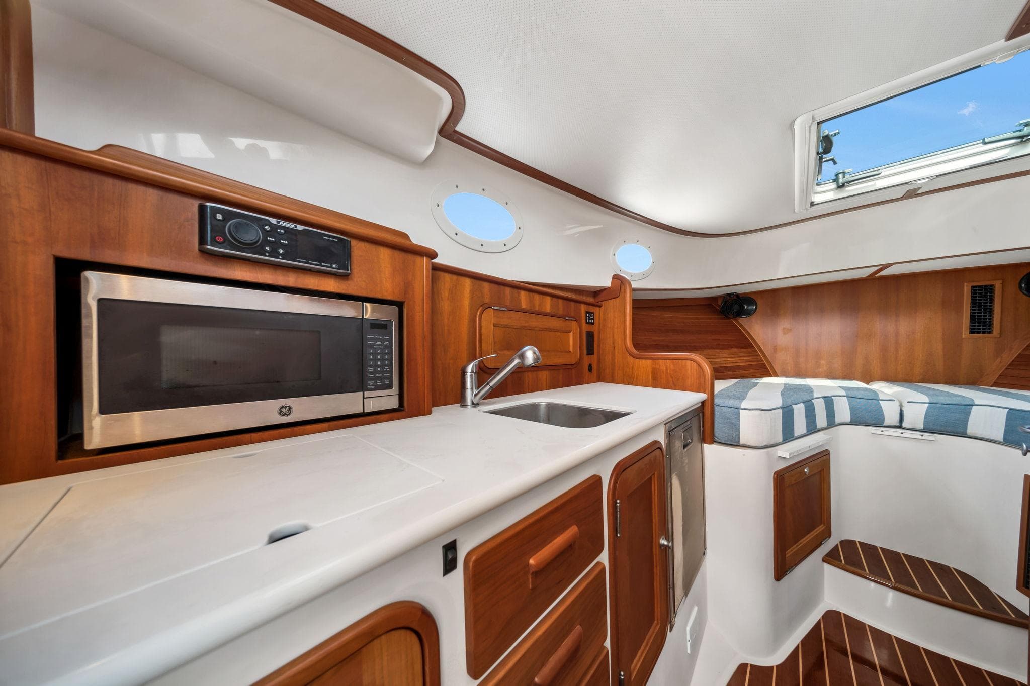 2019 Hinckley Picnic Boat 34 interior with kitchenette, microwave, sink, and seating area.