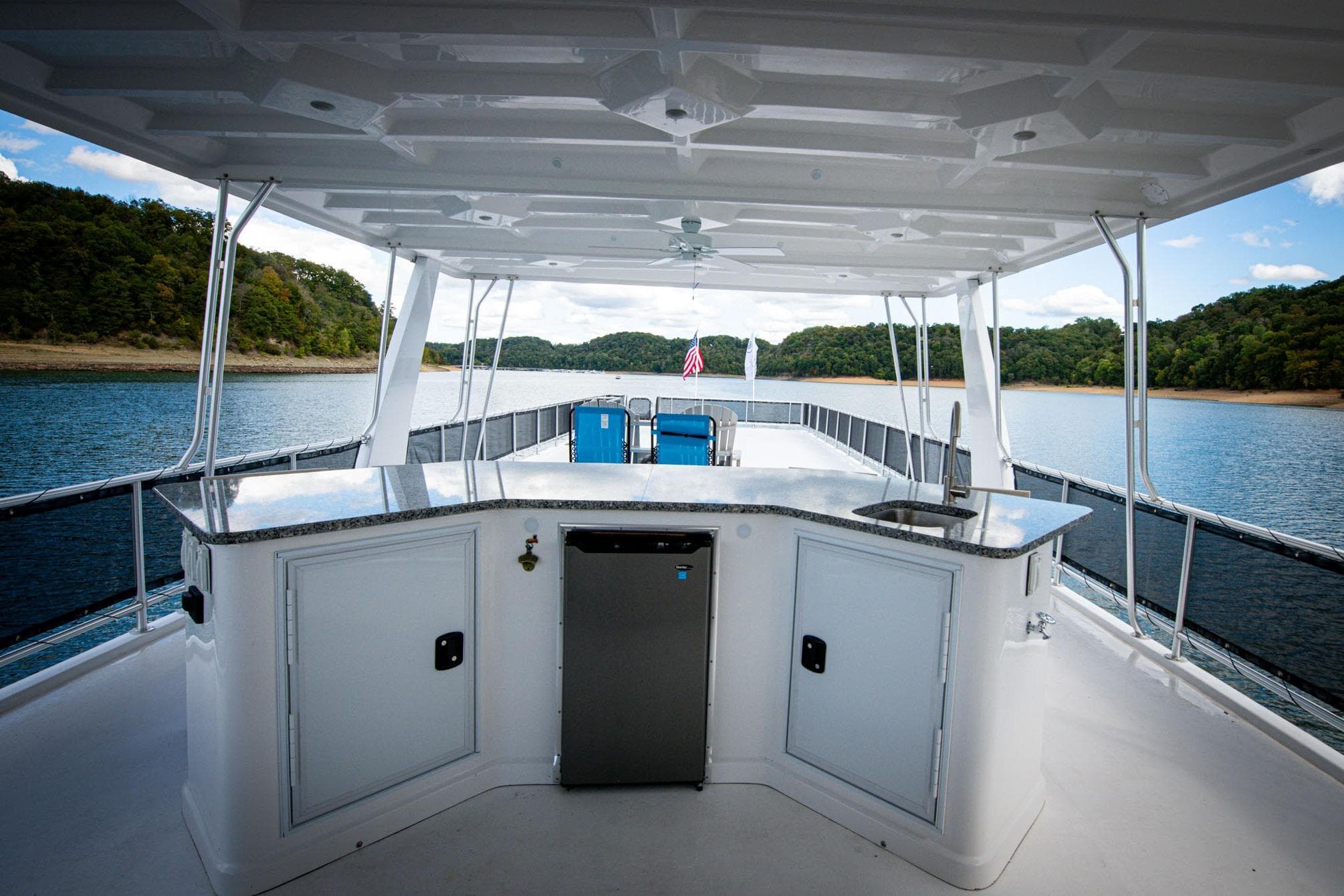 Luxurious 2026 Sumerset Luxe II houseboat with outdoor bar on serene lake.