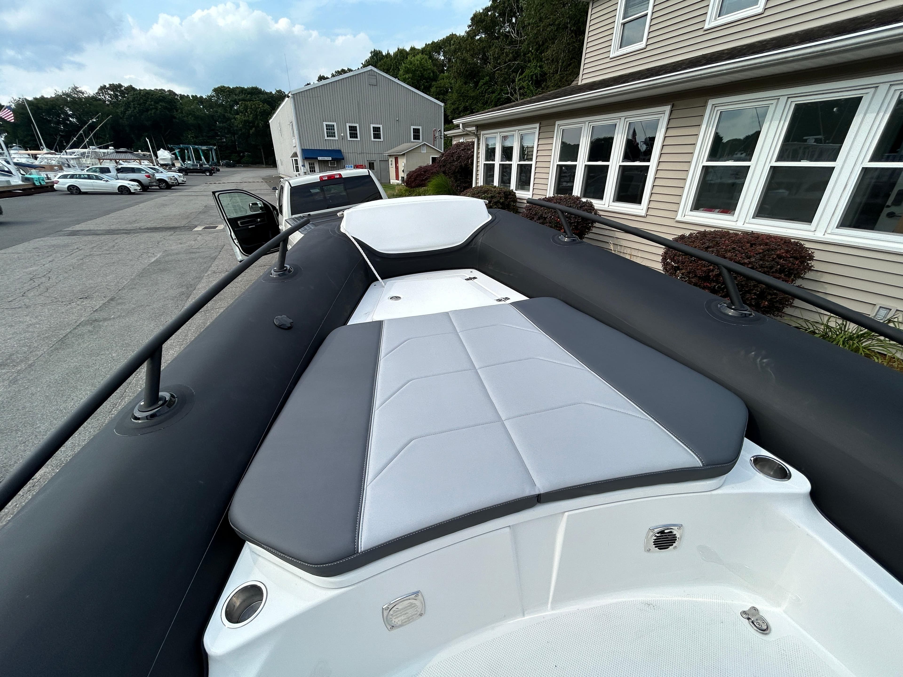 2025 Grand Inflatables G850 boat with cushioned seating, docked near buildings.
