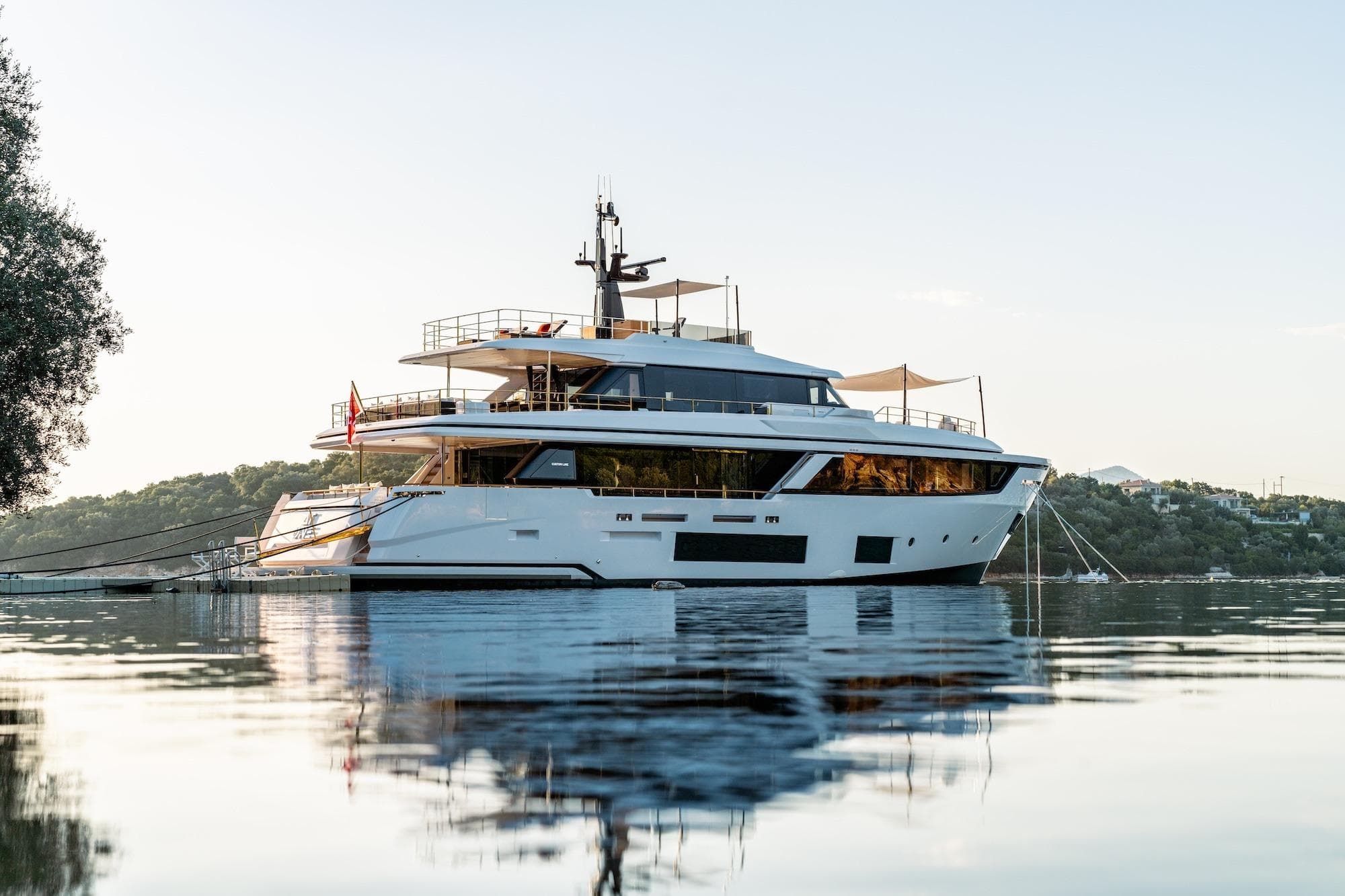 Luxurious 2024 Custom Line Navetta 30 yacht anchored on serene water at sunset.