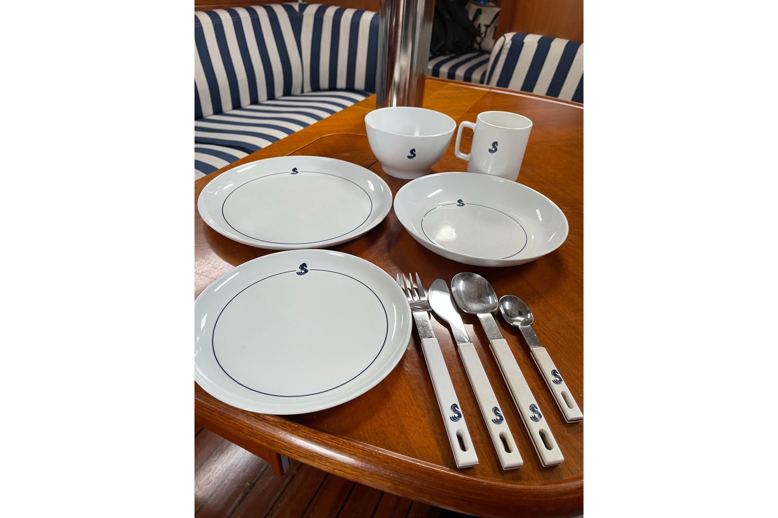 Dining set on Beneteau Oceanis 361 yacht, featuring plates, cups, and cutlery.