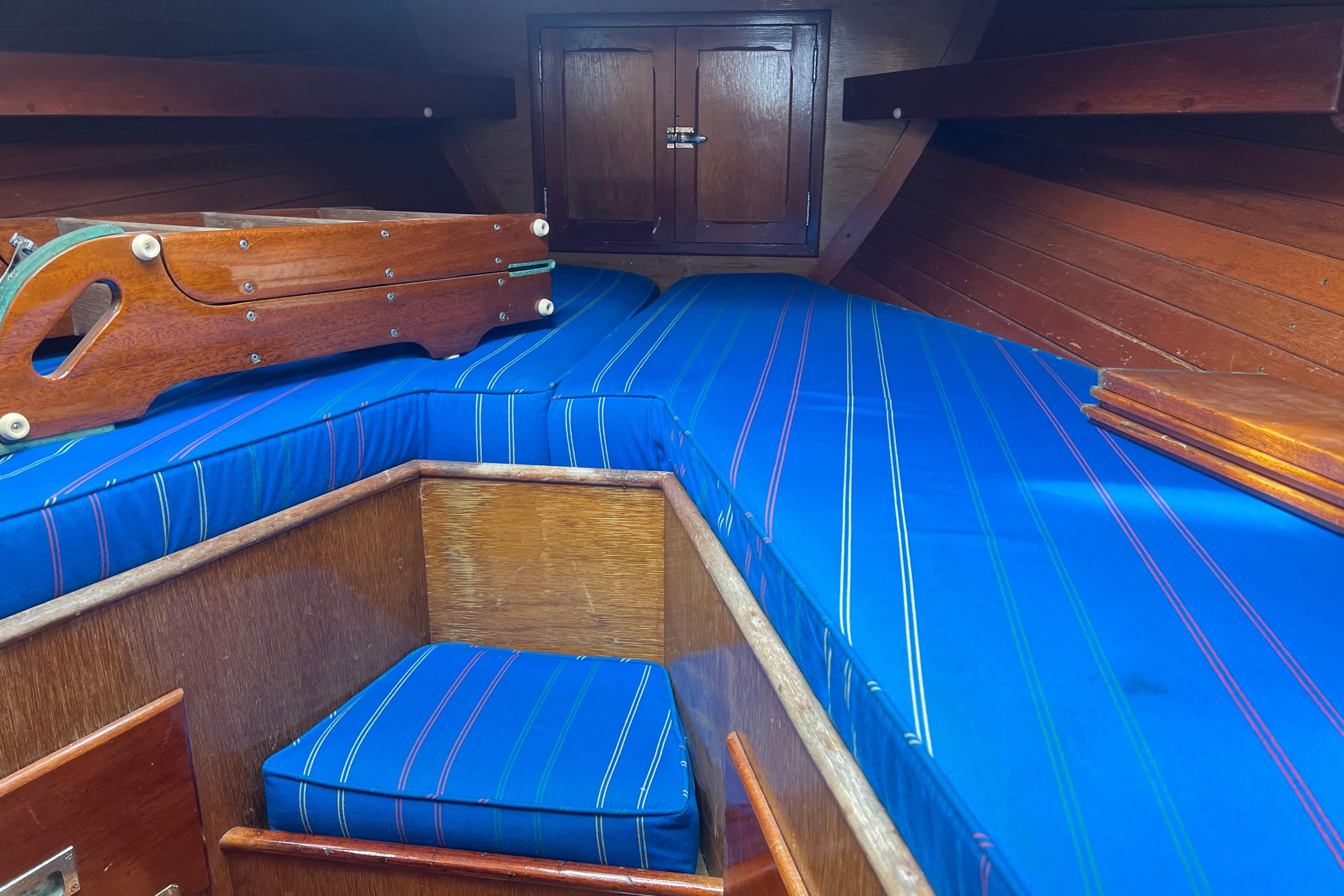 Interior of 1964 Hinckley Pilot 35 Sloop with blue-striped cushions and wooden cabinetry.