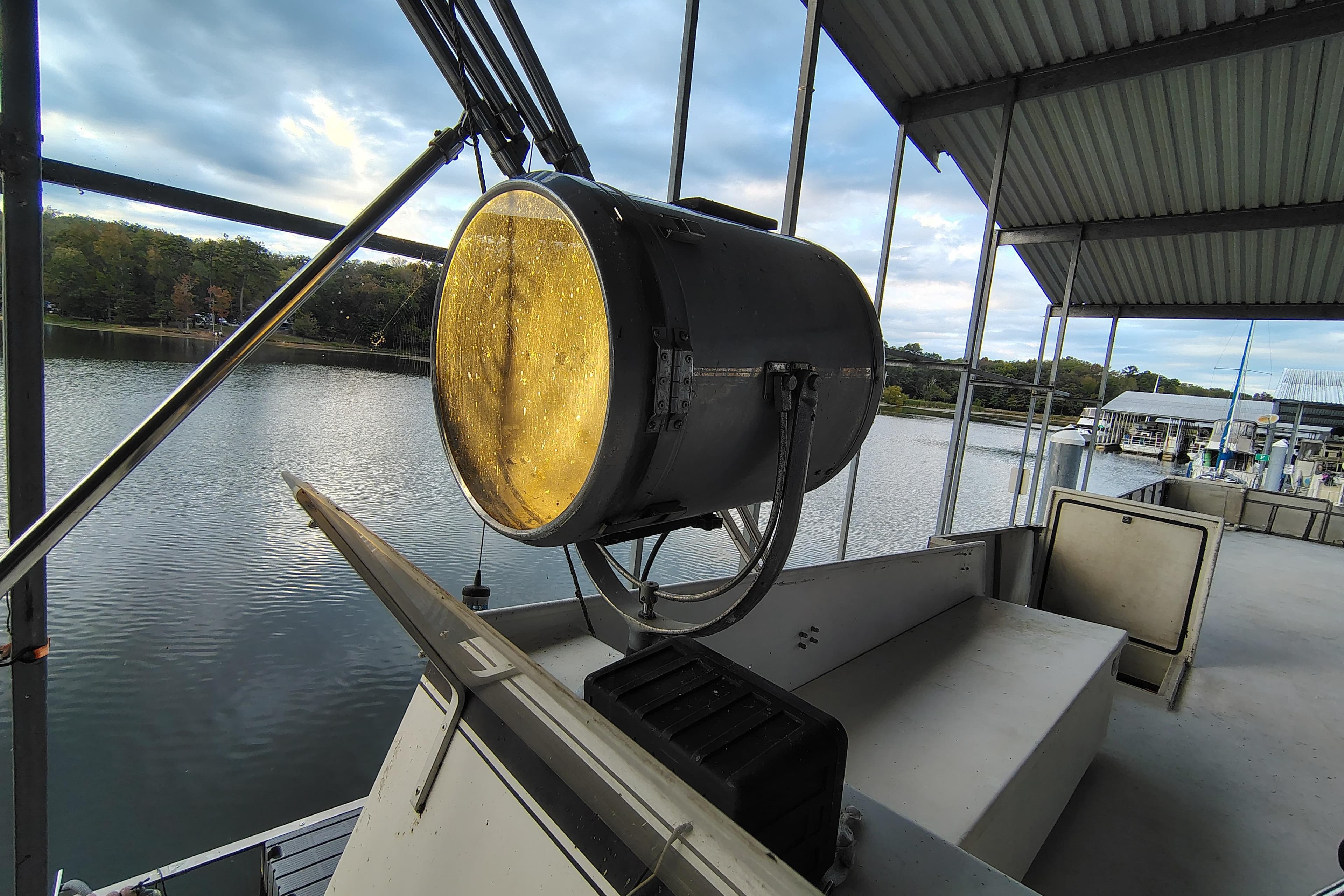 Large spotlight on 1981 Lazy Days 50 boat docked by a serene lake.