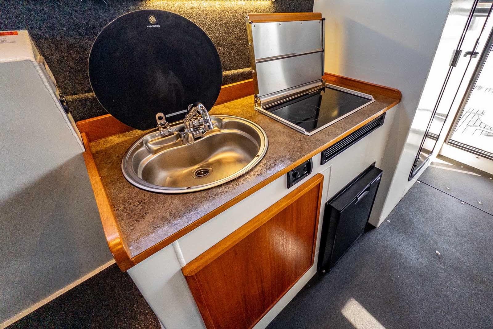 Compact kitchen area in a 2021 Wooldridge 33 Deep Water Explorer boat, featuring a sink and stove.