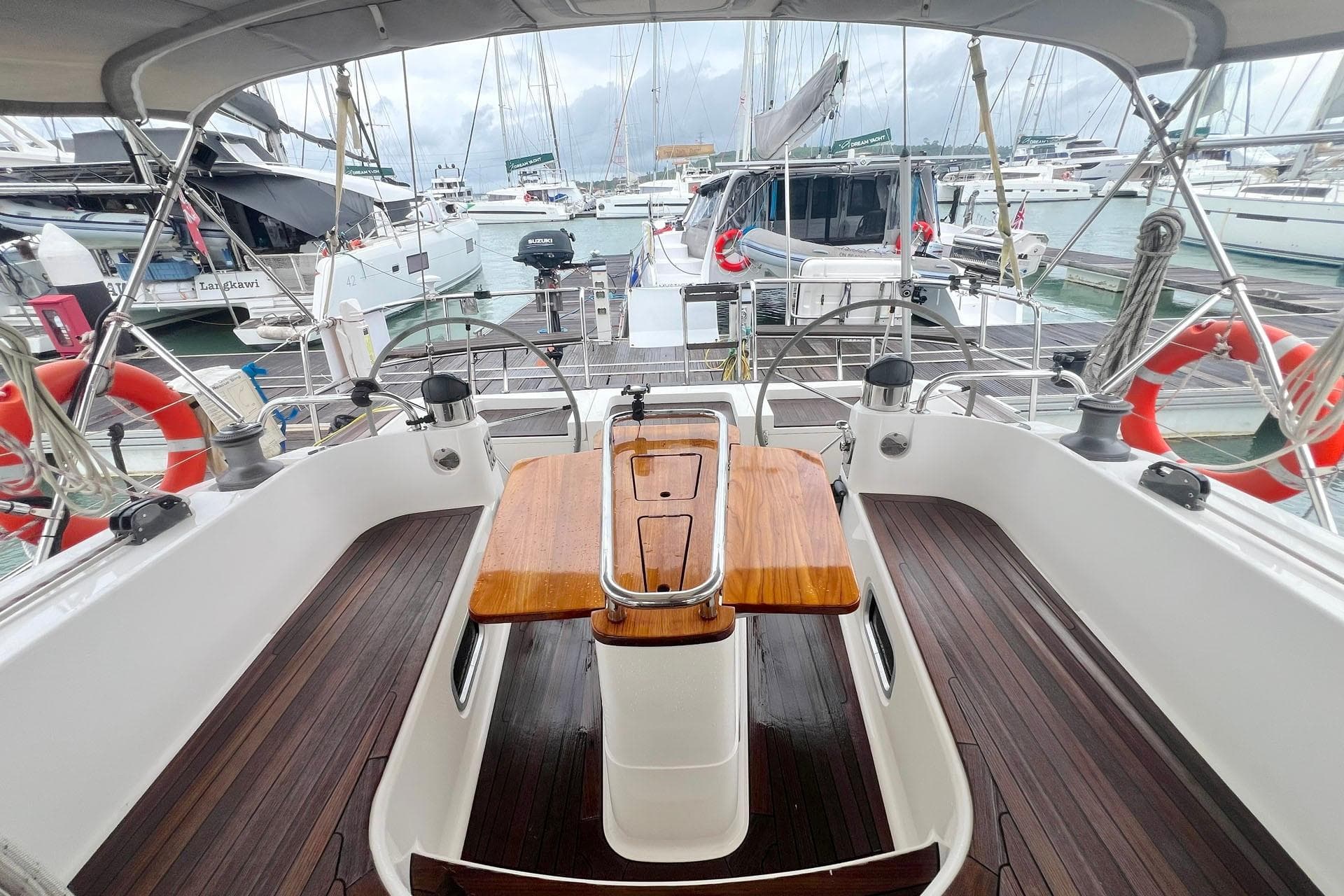 Cockpit view of 2014 Southerly 47 yacht docked at marina with wooden table and dual steering wheels.