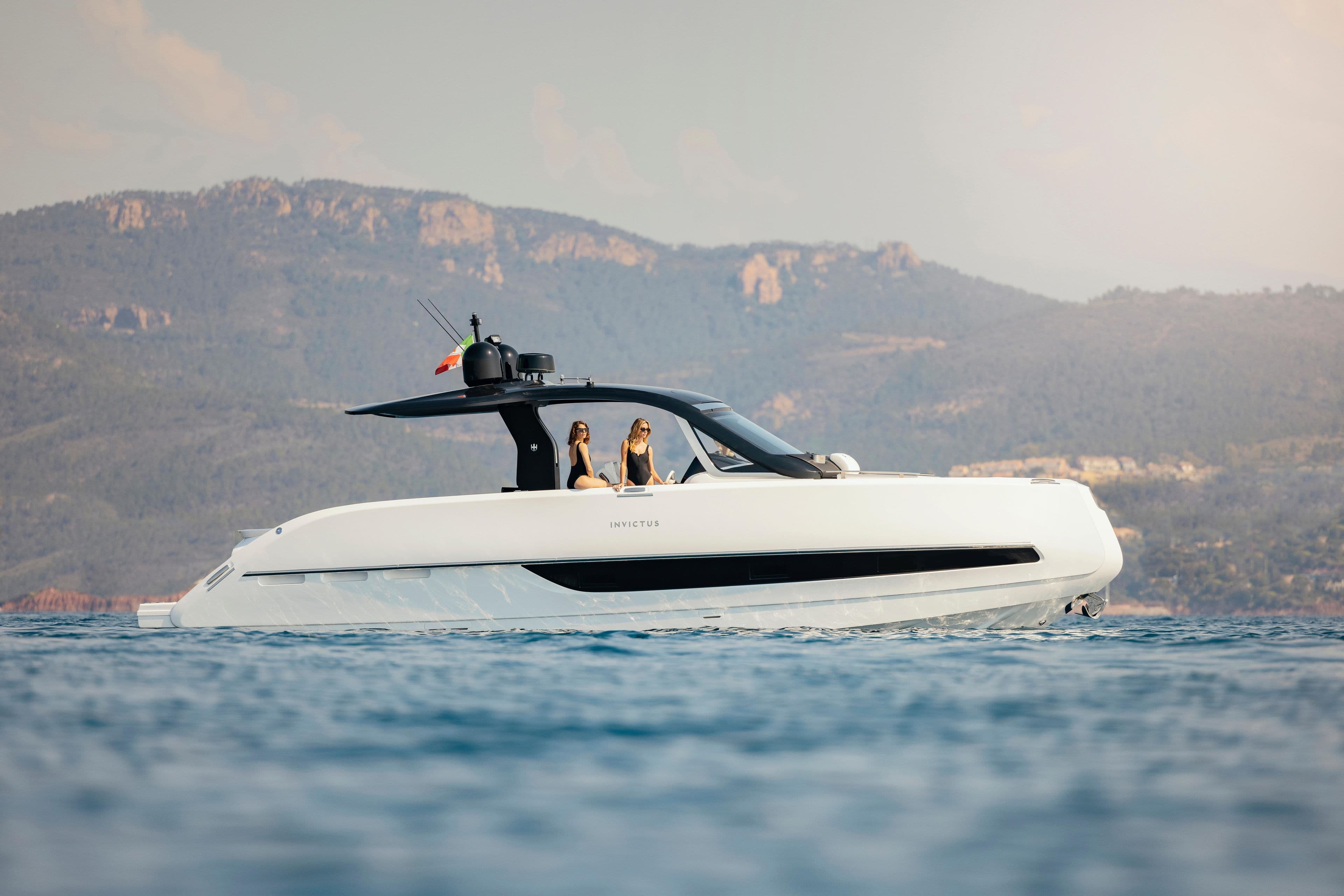 2025 Invictus TT420 yacht cruising on serene waters with mountainous backdrop.