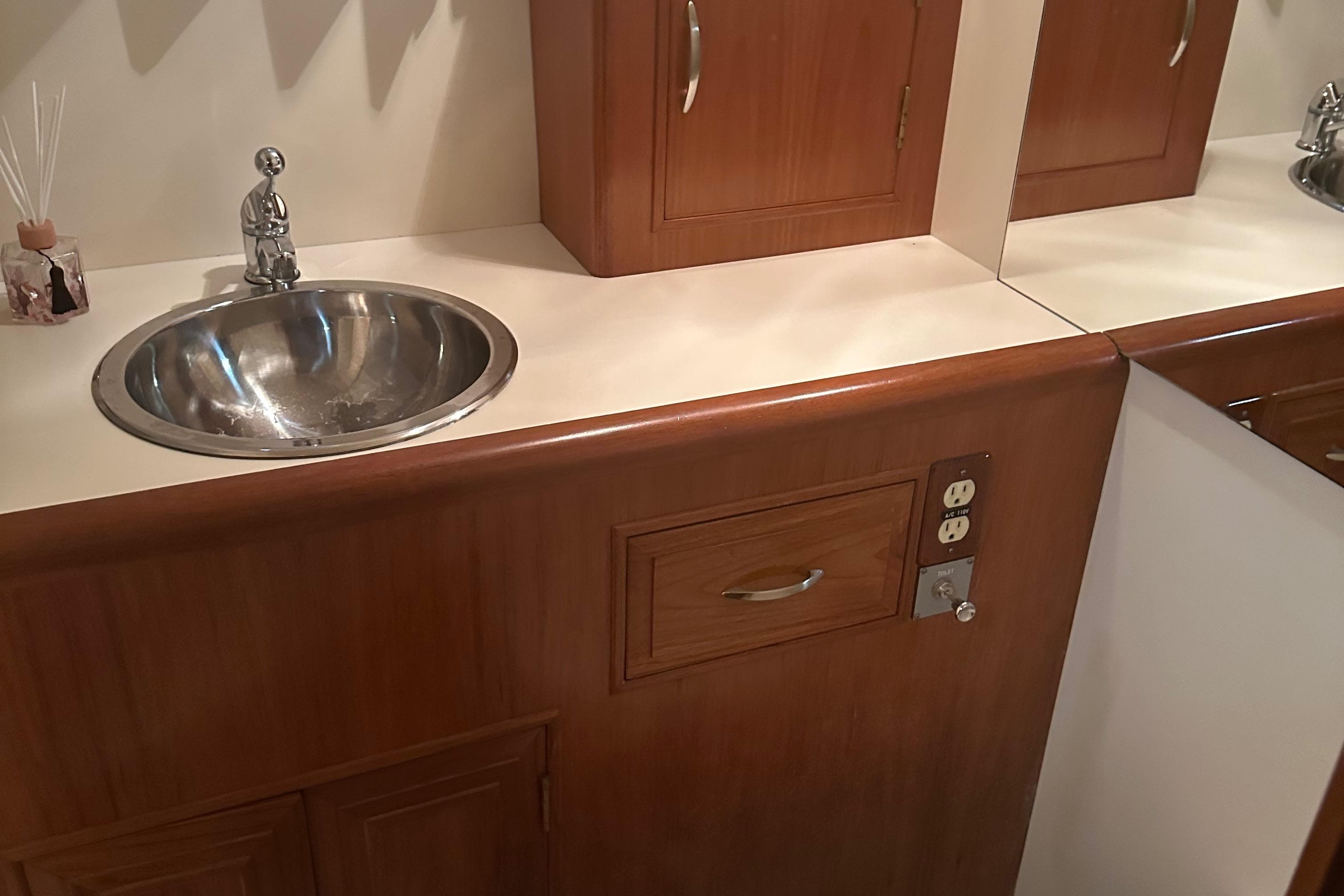 1988 Ocean Alexander 42 aft cabin bathroom with wooden cabinetry and stainless steel sink.