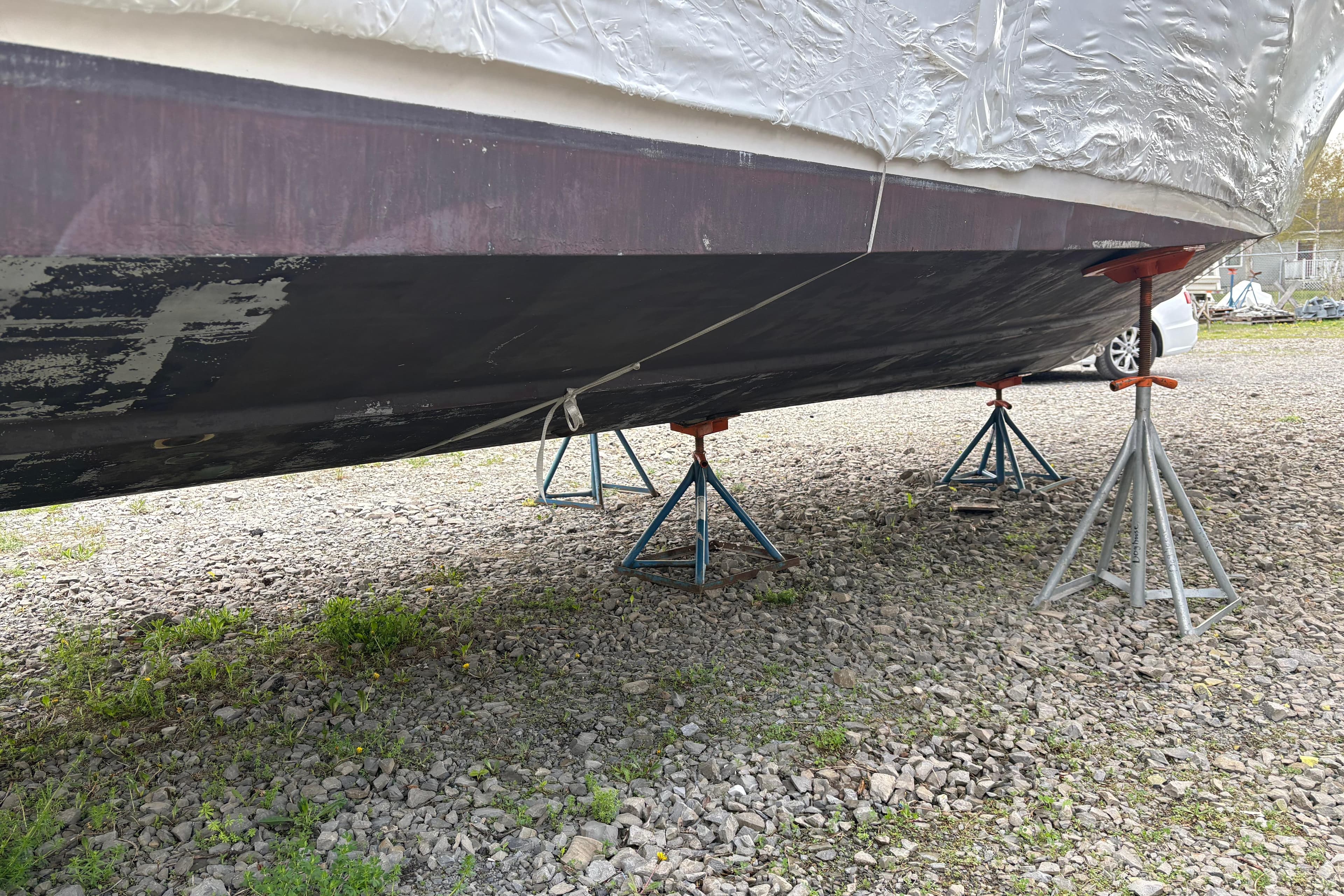 1999 Four Winns 328 Vista boat on stands, hull view, gravel surface.