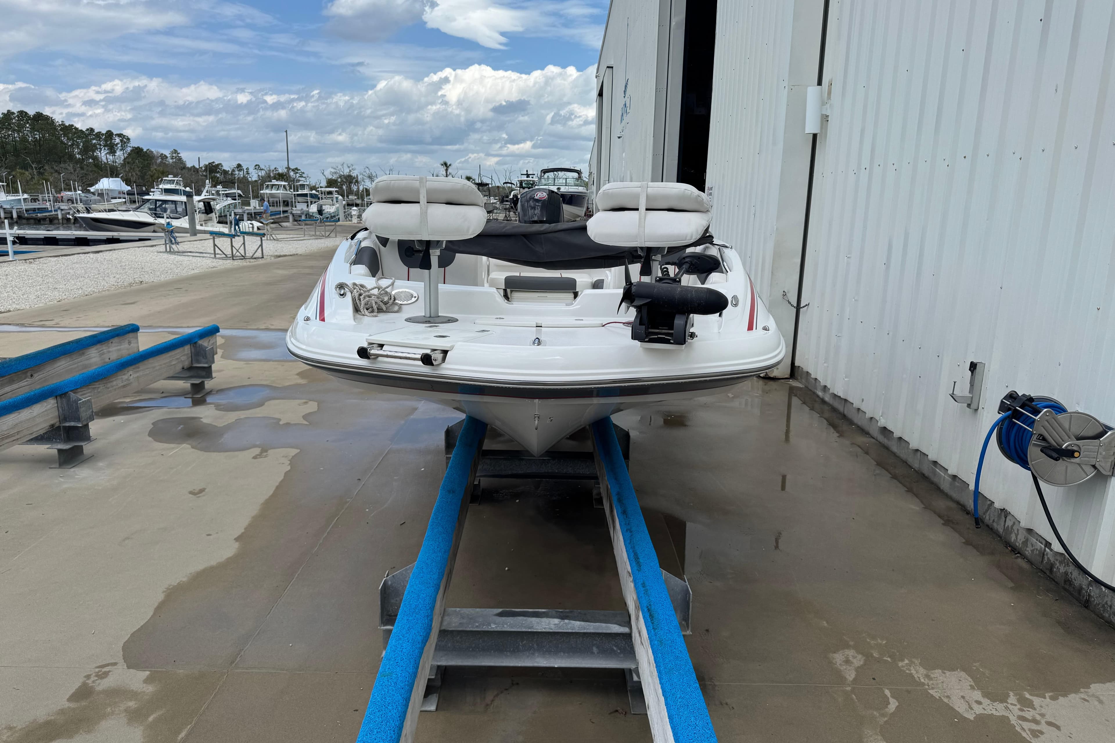 White 2022 Tahoe 1950 boat on a dock, with marina and cloudy sky background.