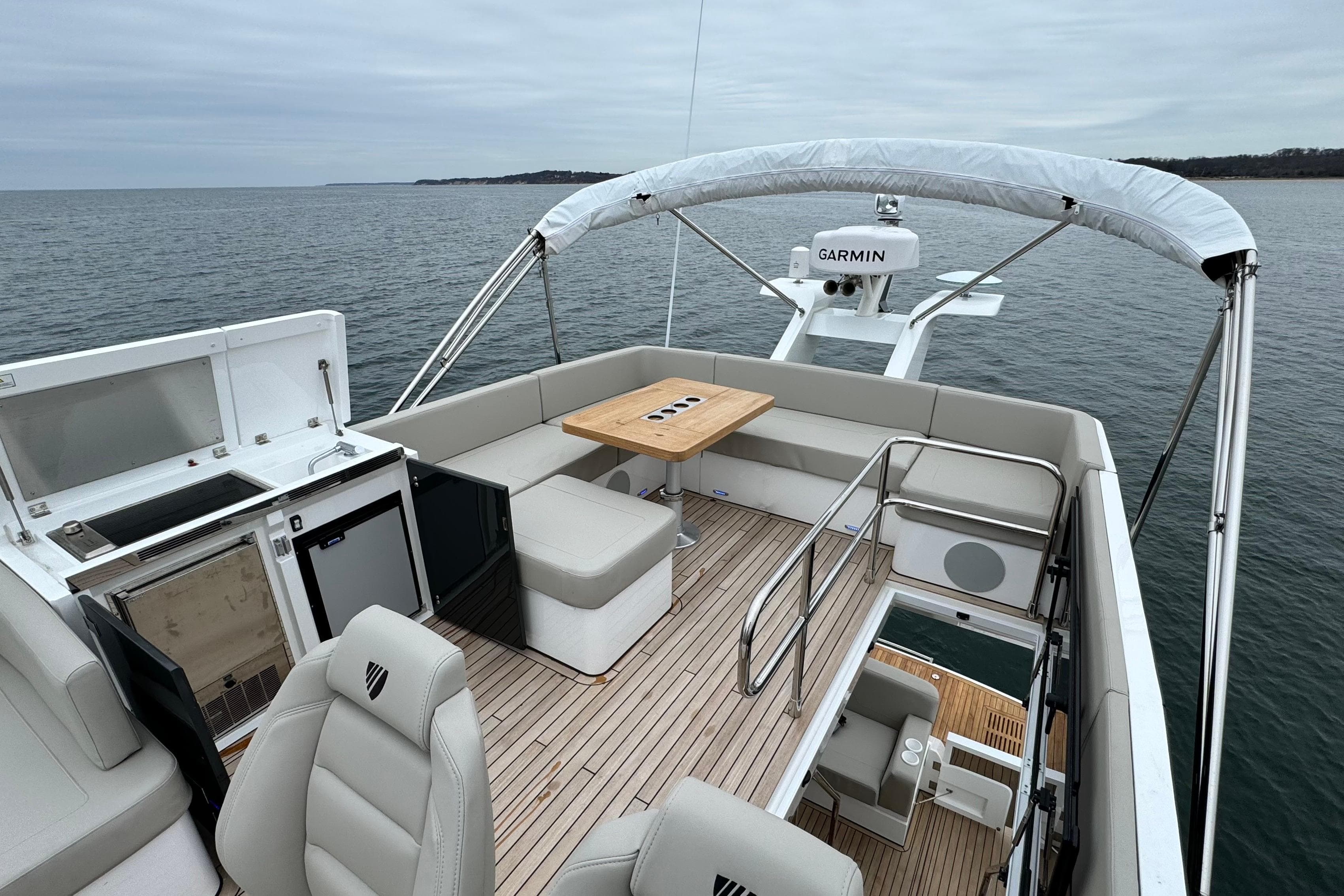 2024 Fairline Squadron 50 yacht flybridge with seating, table, and Garmin equipment on open water.