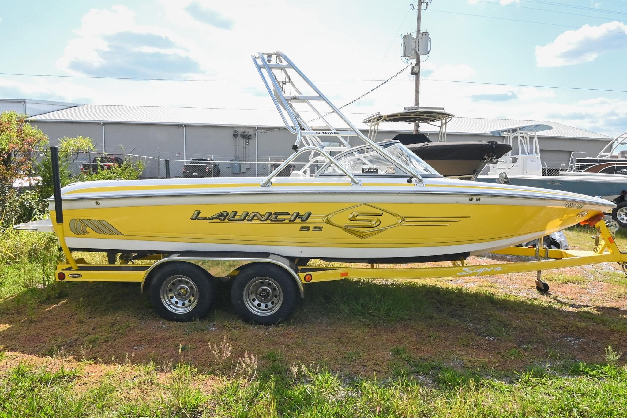 Yellow 2004 Supra Launch SS boat on trailer, parked outdoors.