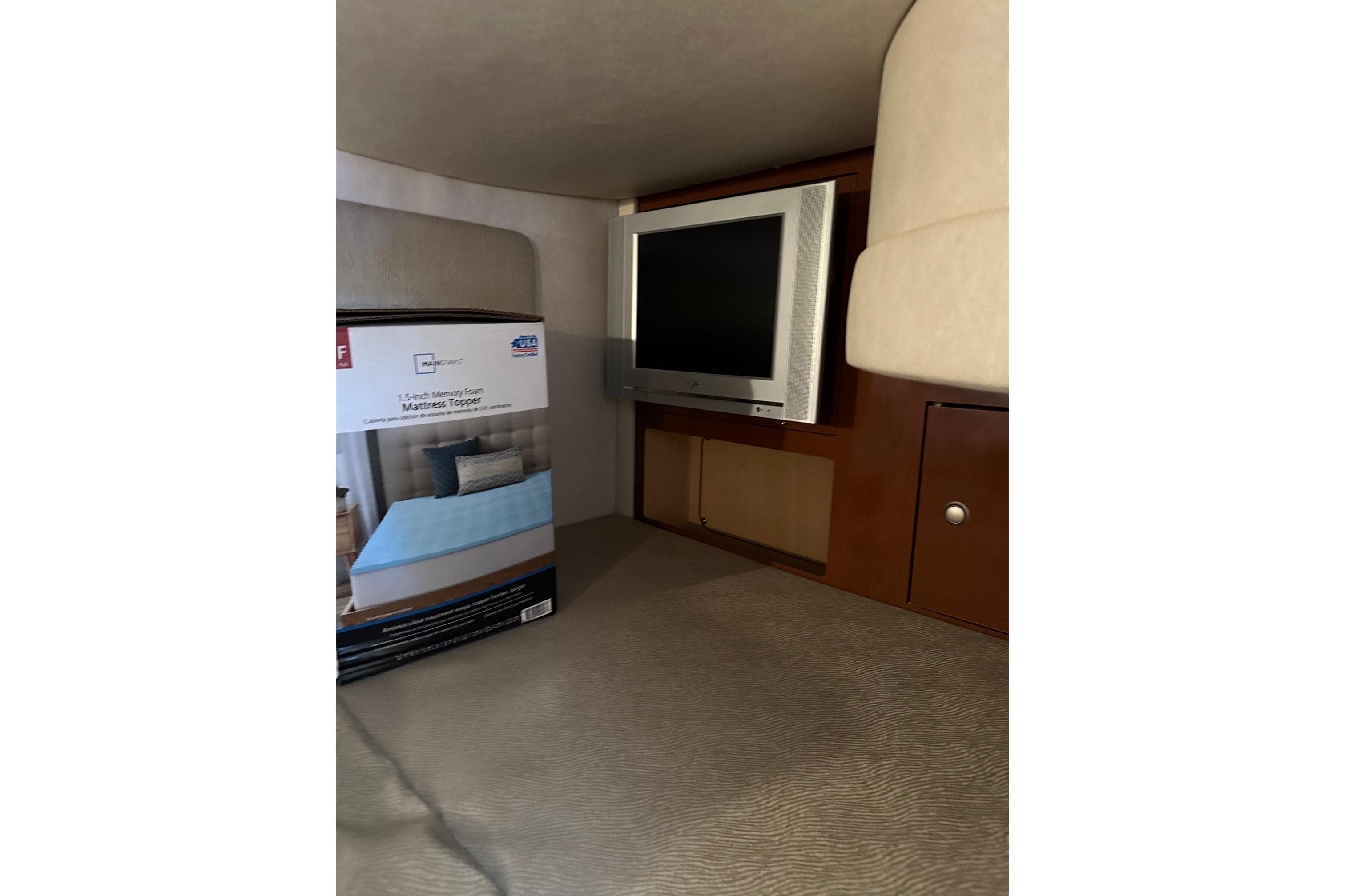 Interior of 2008 Sea Ray 290 Sundancer with TV and mattress topper box.