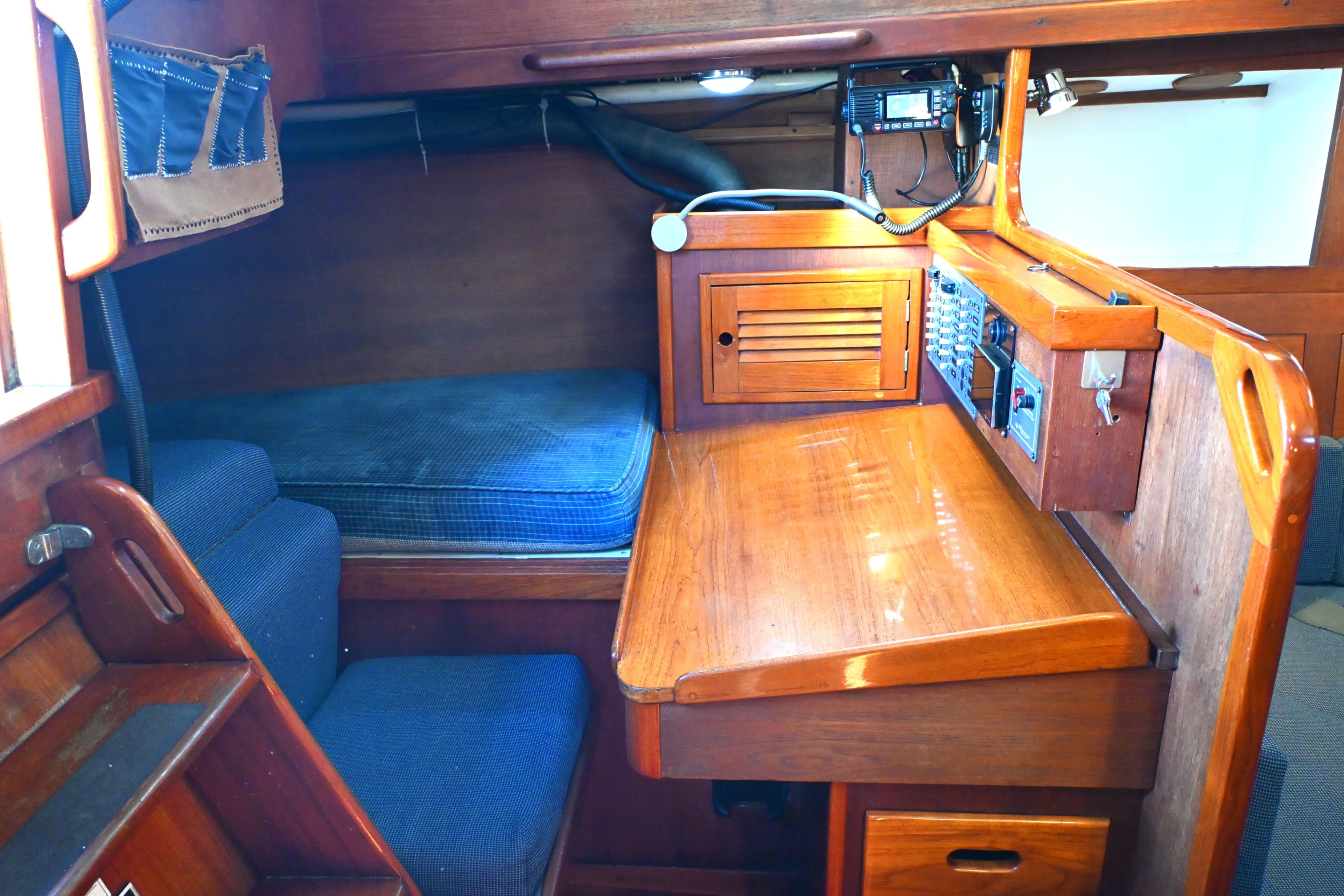 Cozy 1980 Tartan 37 sailboat interior with wooden desk and blue cushions.
