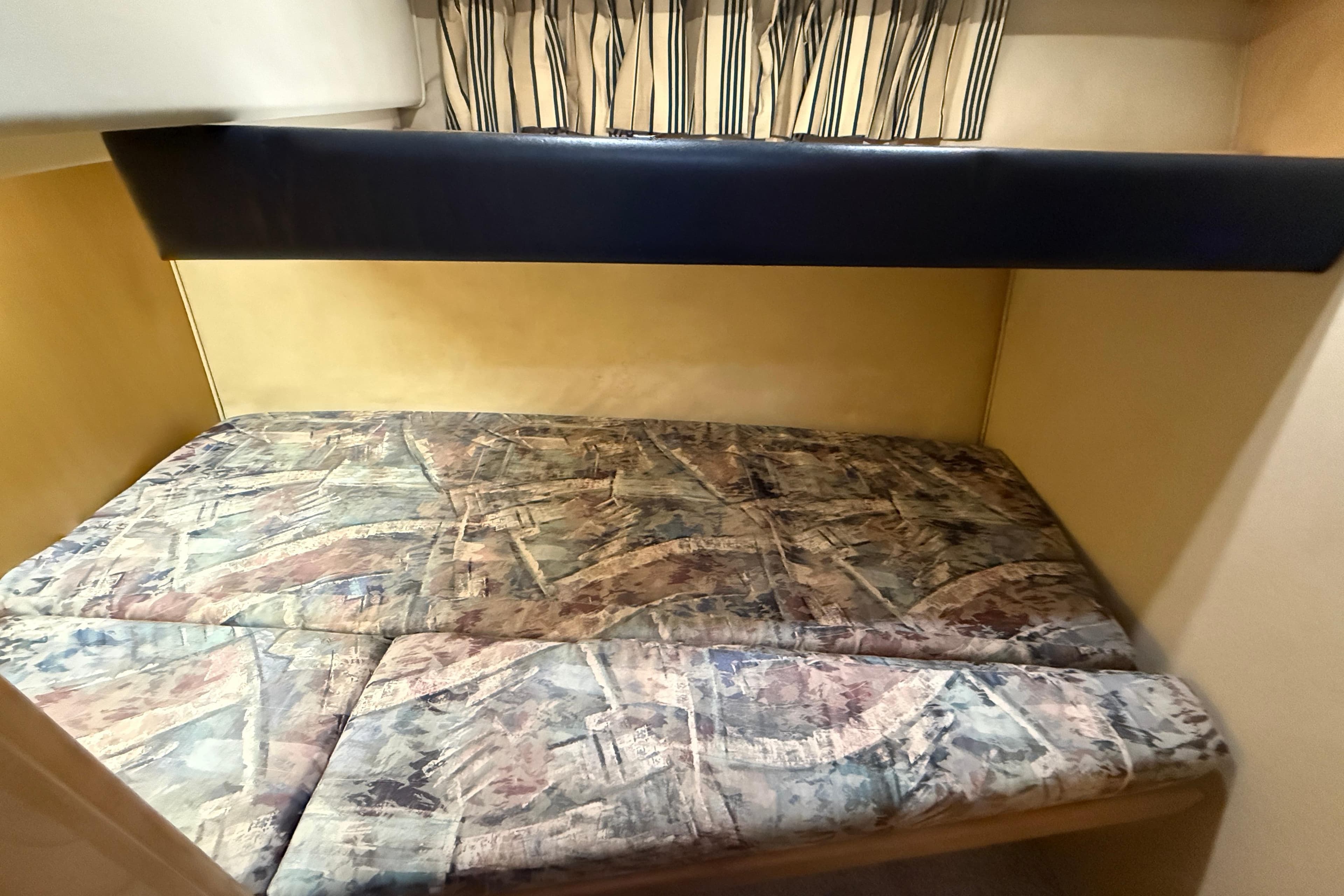 Interior cabin of 1996 Carver 370 Voyager with patterned bedding and striped curtains.