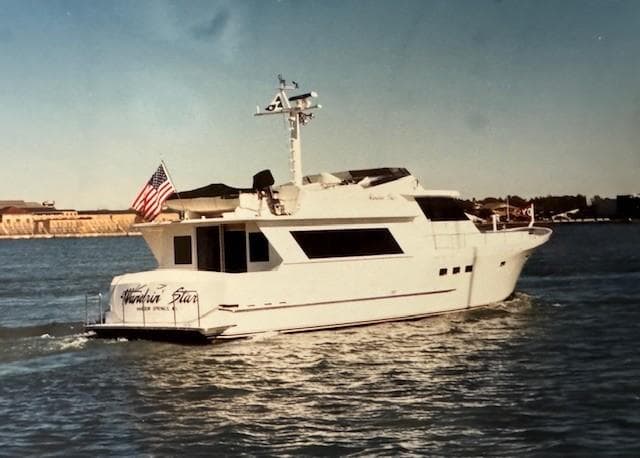 1990 Motor Yacht 70 Brata cruising on open water, American flag displayed.