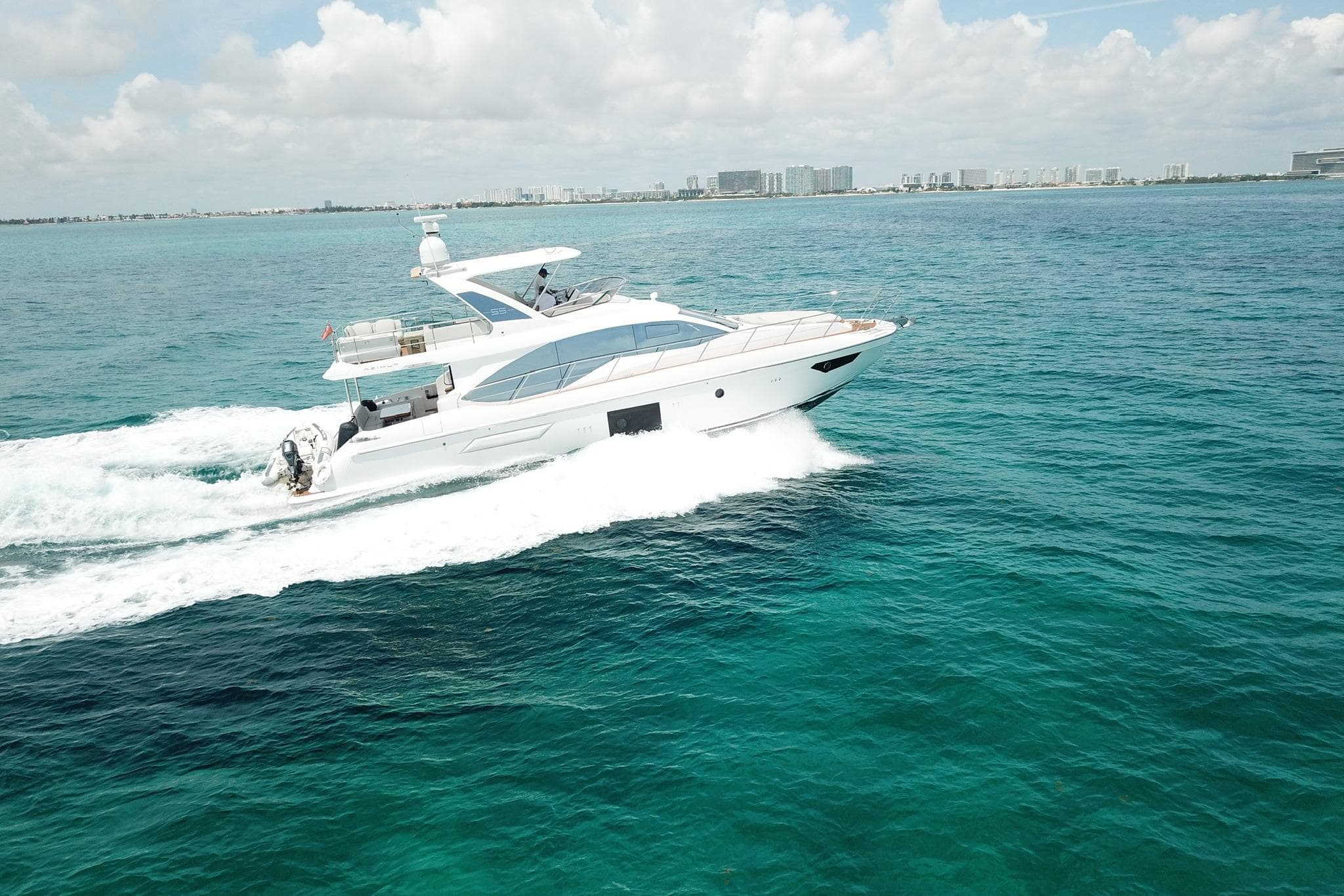 Luxury Azimut 55 yacht cruising on clear blue ocean, 2021 model.