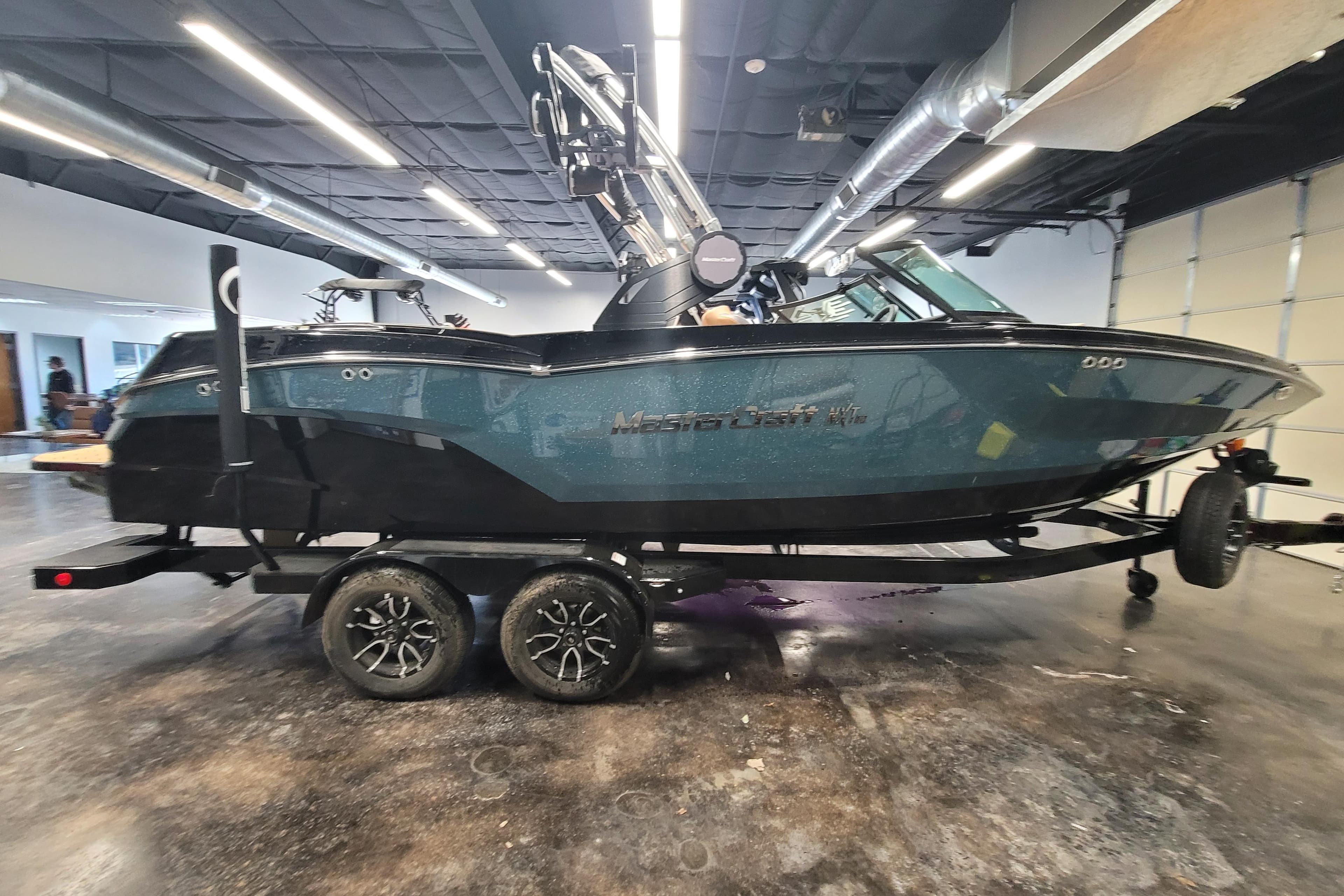 2025 MasterCraft NXT23 boat on trailer in a showroom setting.