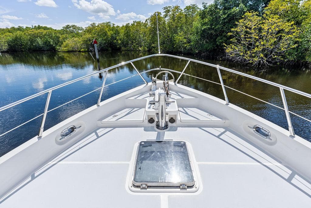 Bow of Selene Solo 2000 yacht navigating calm river with lush greenery.