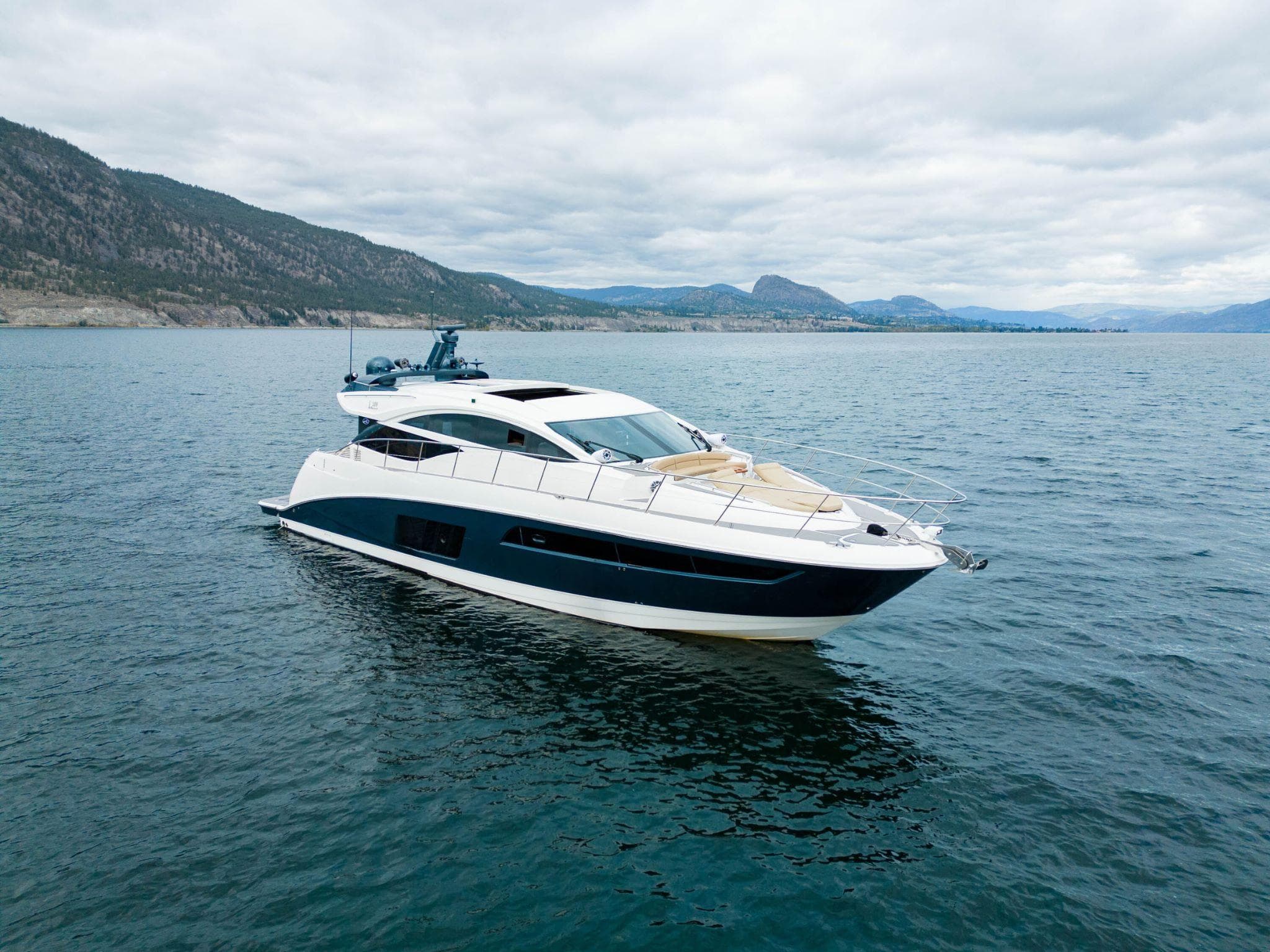 2016 Sea Ray L590 yacht cruising on a scenic lake with mountainous backdrop.