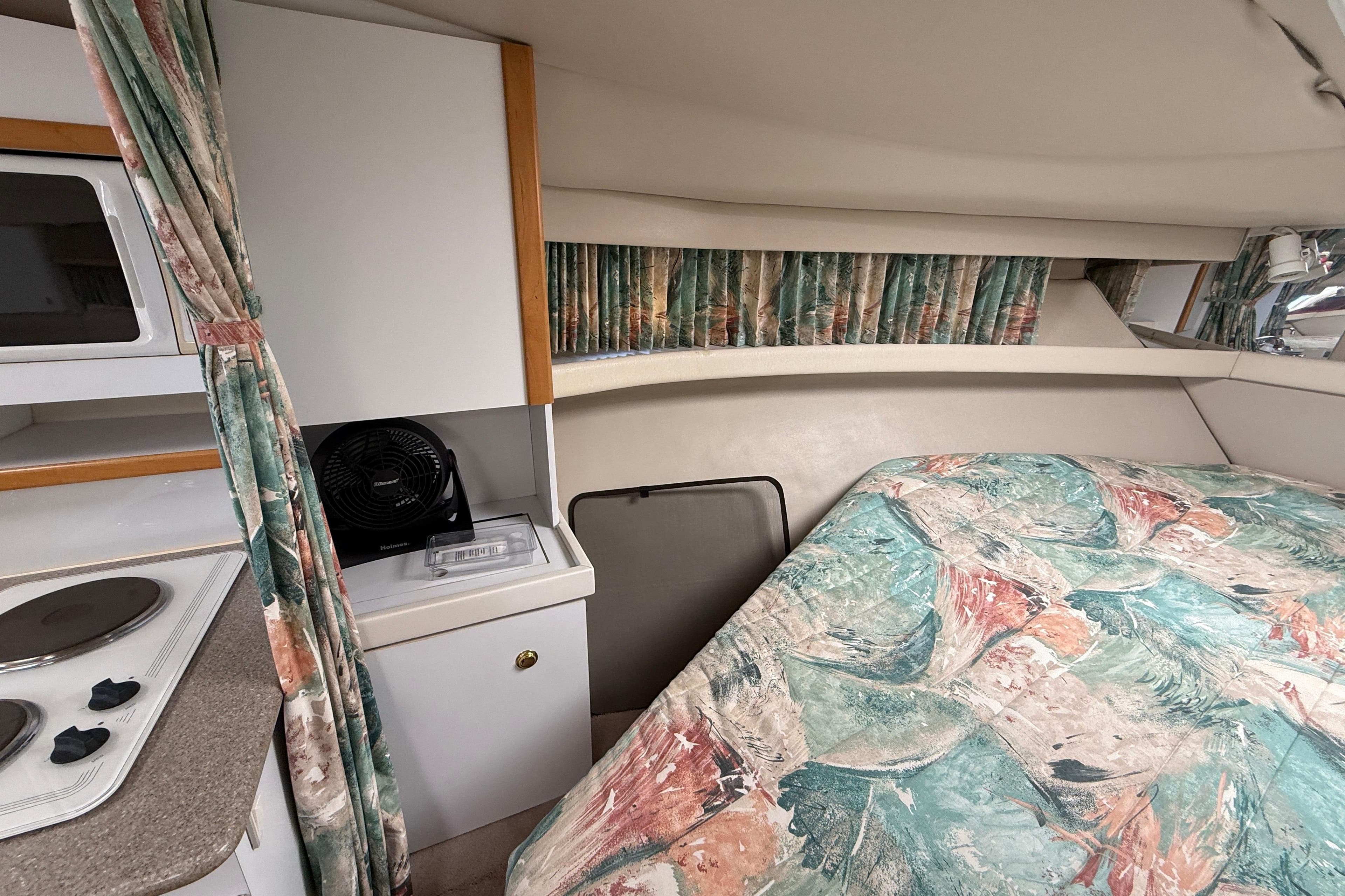 1998 Formula 34 Performance Cruiser interior with bed, kitchenette, and patterned curtains.