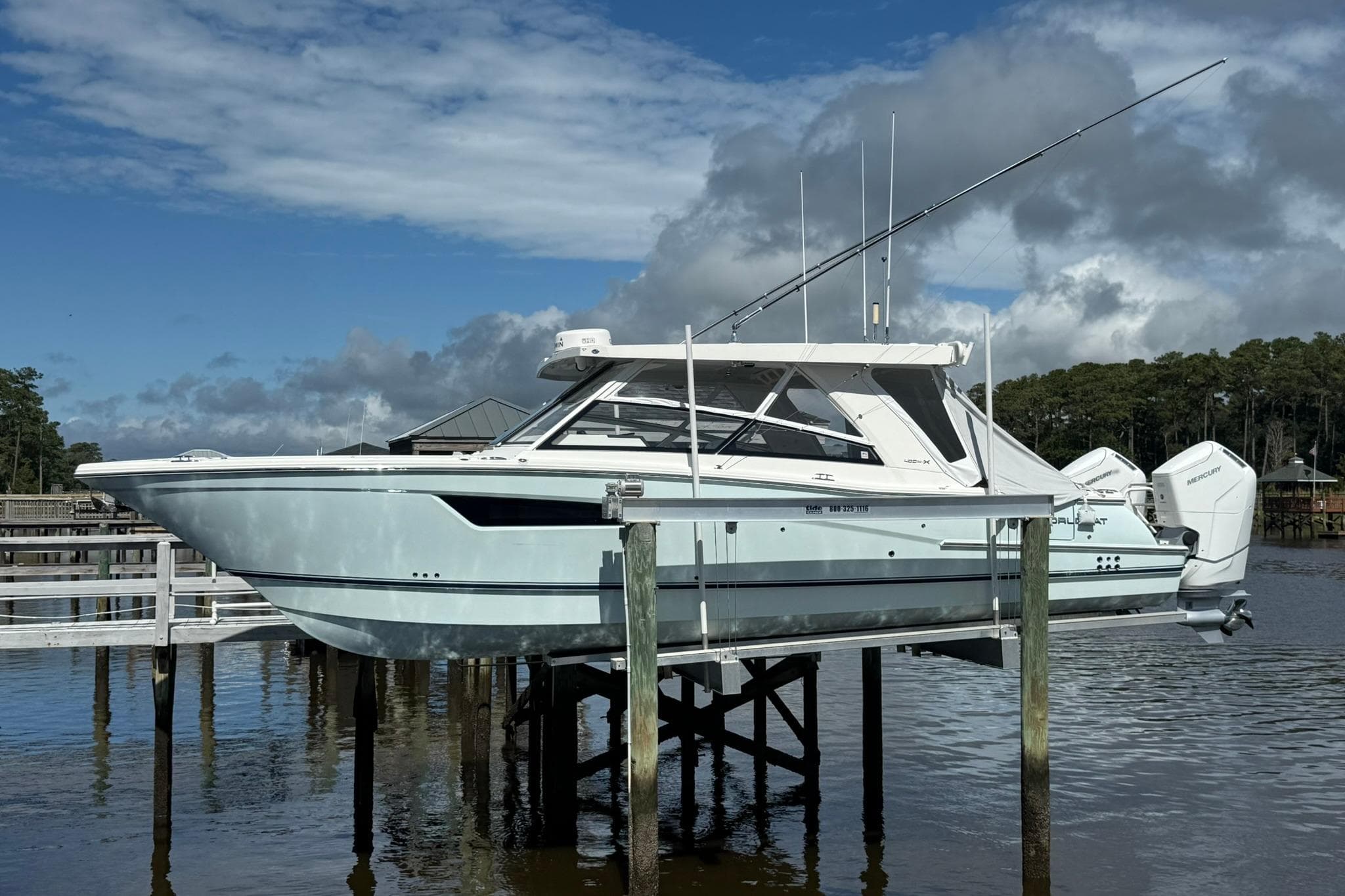 2023 World Cat 400 DC-X boat on lift, dockside, under cloudy sky.