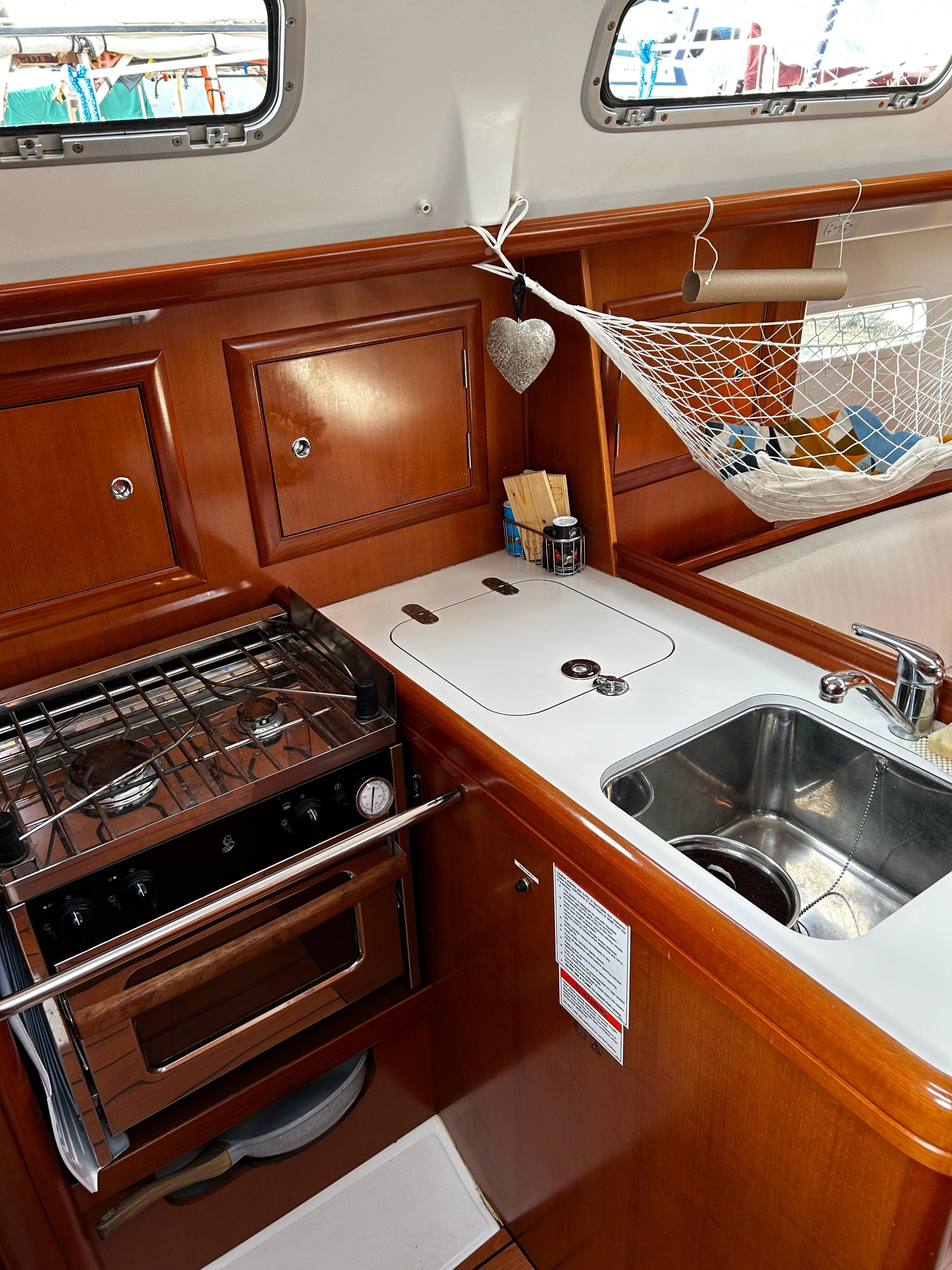 2007 Beneteau Oceanis Clipper 323 yacht kitchen with stove, sink, and wooden cabinetry.