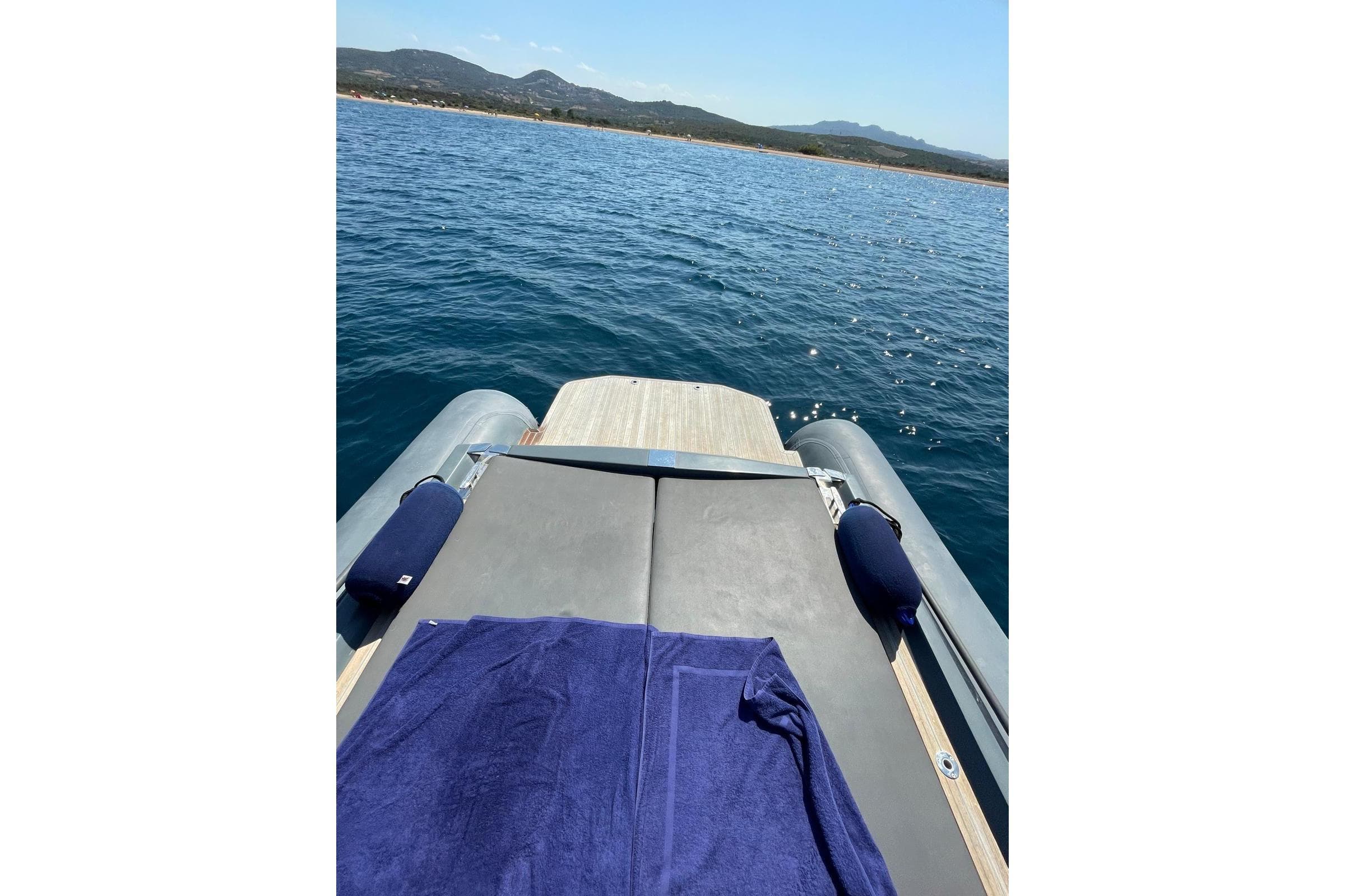 Luxury yacht deck with blue towel, overlooking serene ocean and distant hills. Dariel Phantasia 2009.