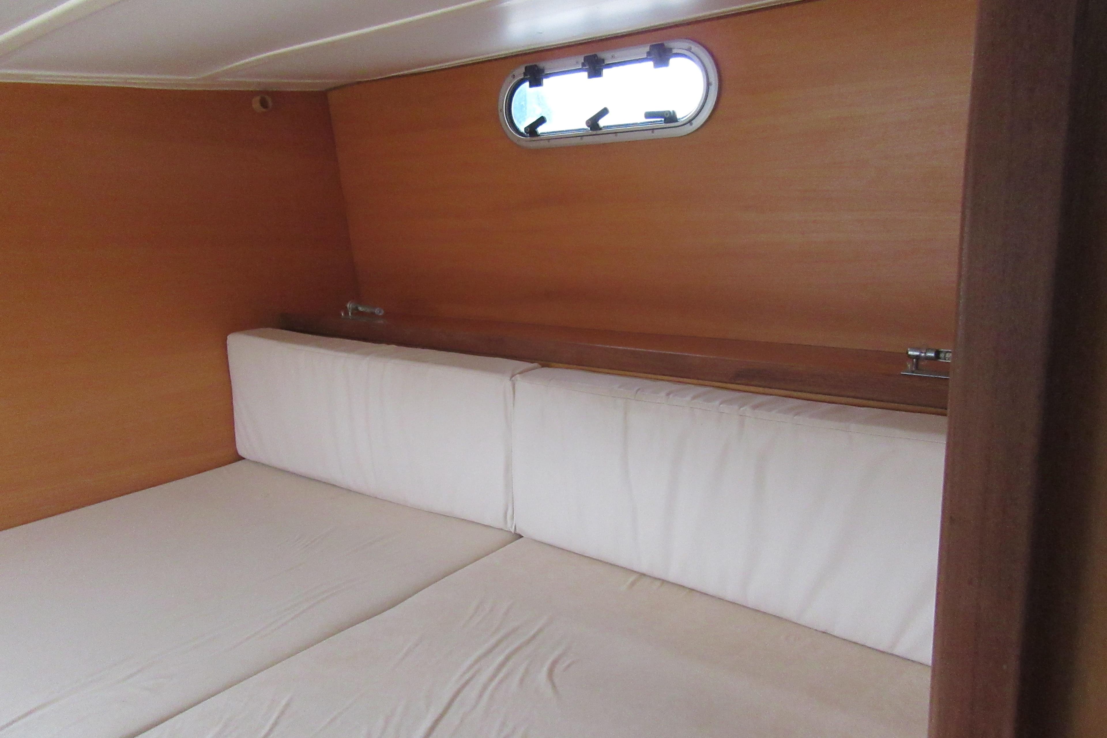 Interior cabin of 2001 Catana 471 yacht with wooden walls and white cushions.