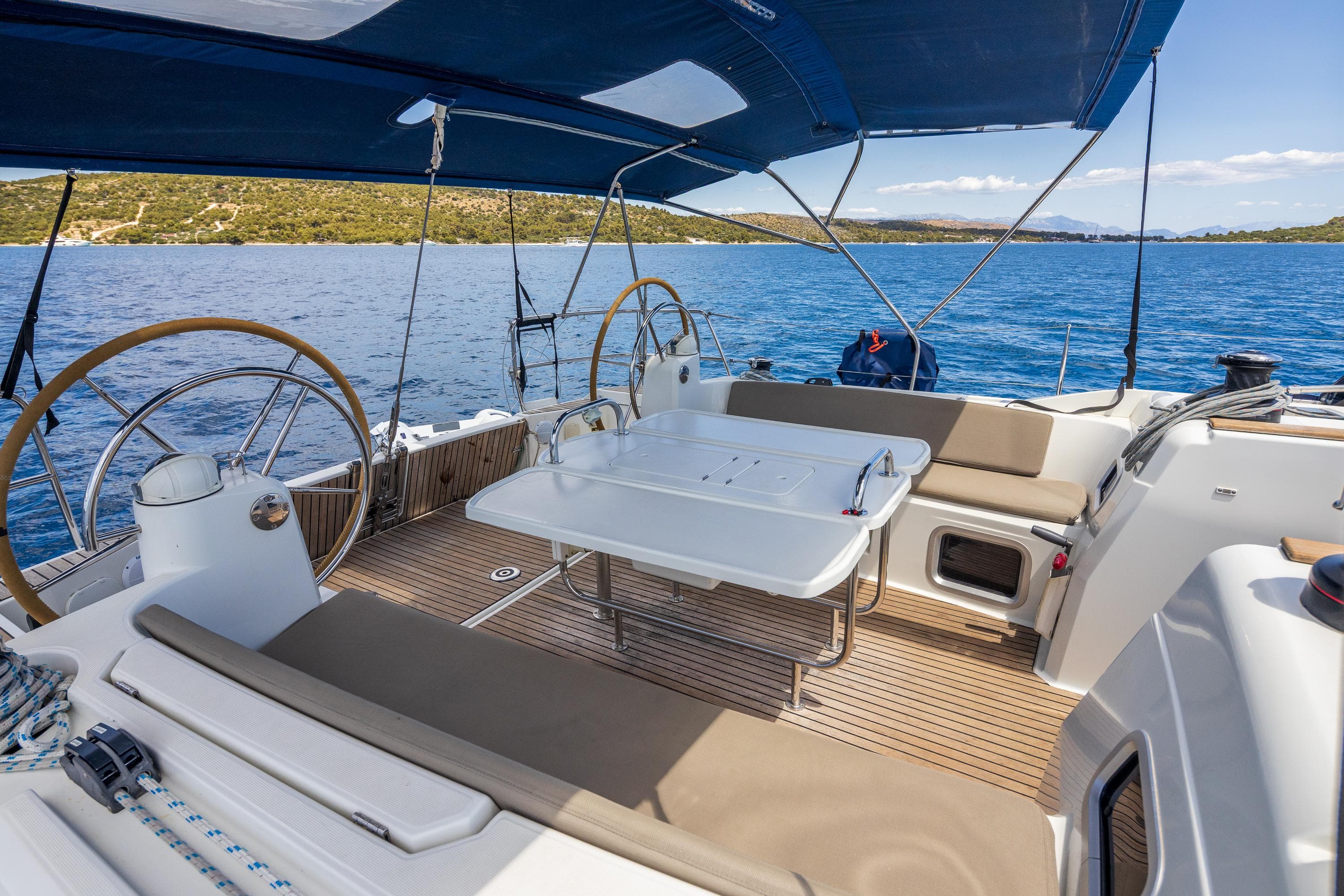2018 Jeanneau Sun Odyssey 519 sailboat deck with seating, table, and dual steering wheels.