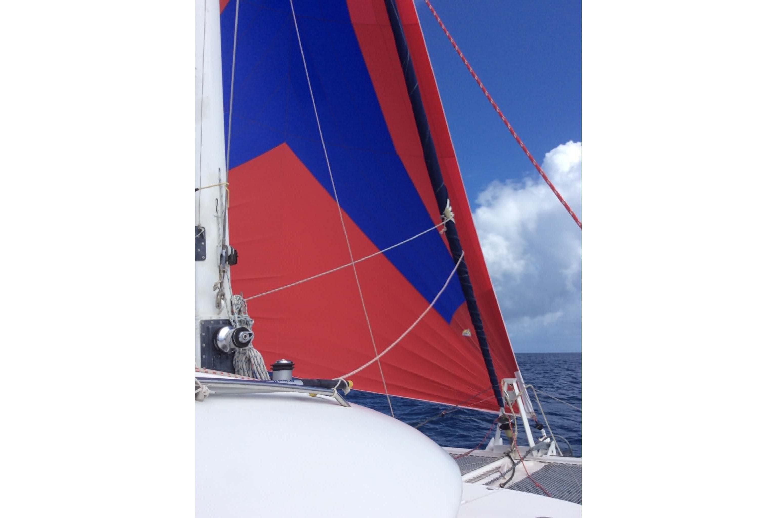 Sailing on a 2002 Lagoon 470 catamaran with vibrant red and blue sails.
