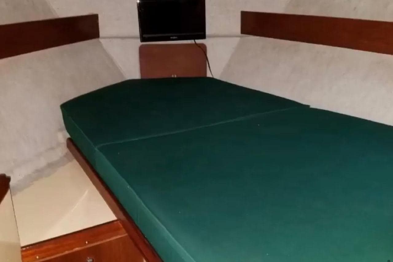 Interior cabin of 1987 Westerly Duo 29 sailboat with green cushions and a small TV.