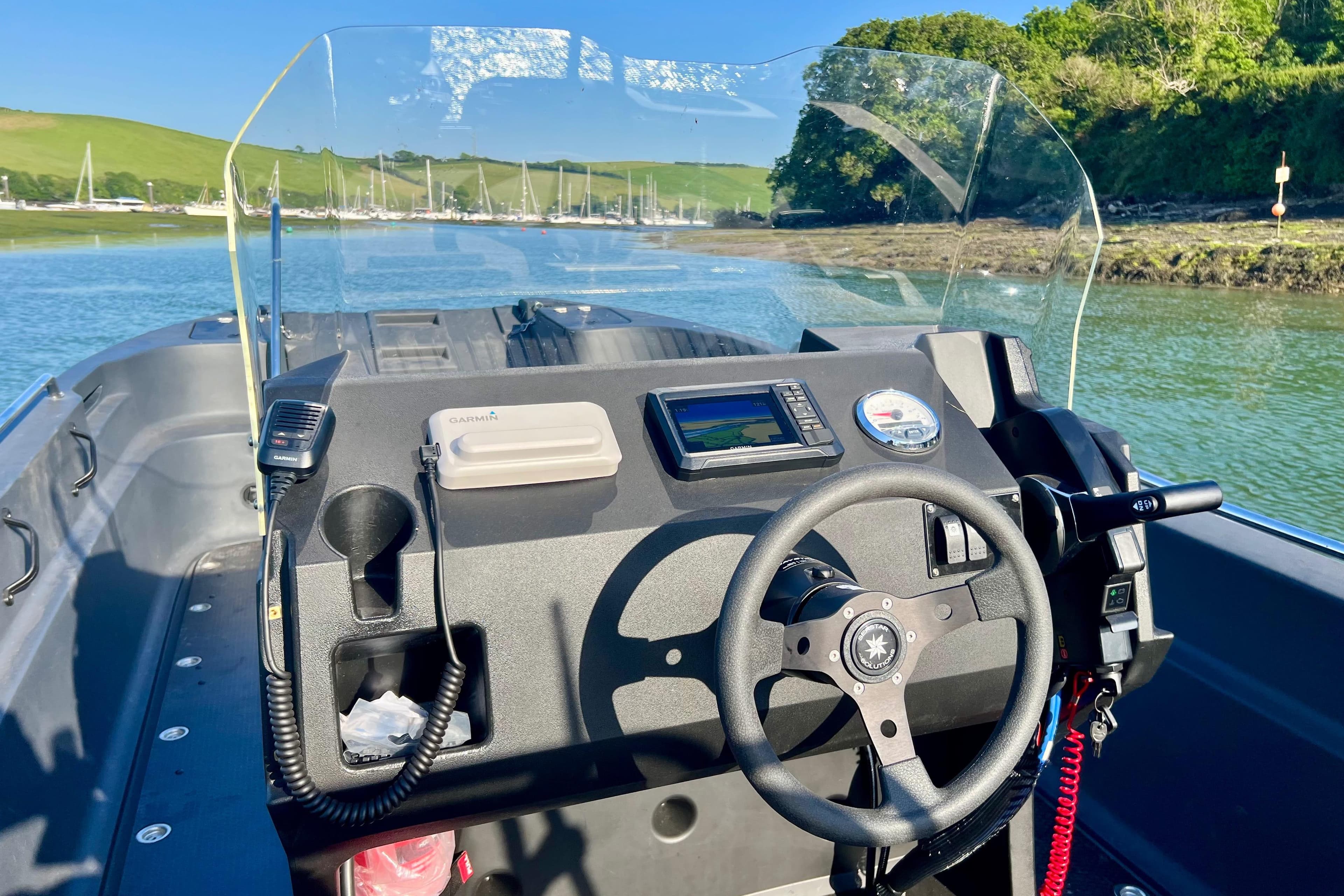 2026 Pioner Multi 3 Pro boat dashboard with steering wheel and navigation system on a sunny day.