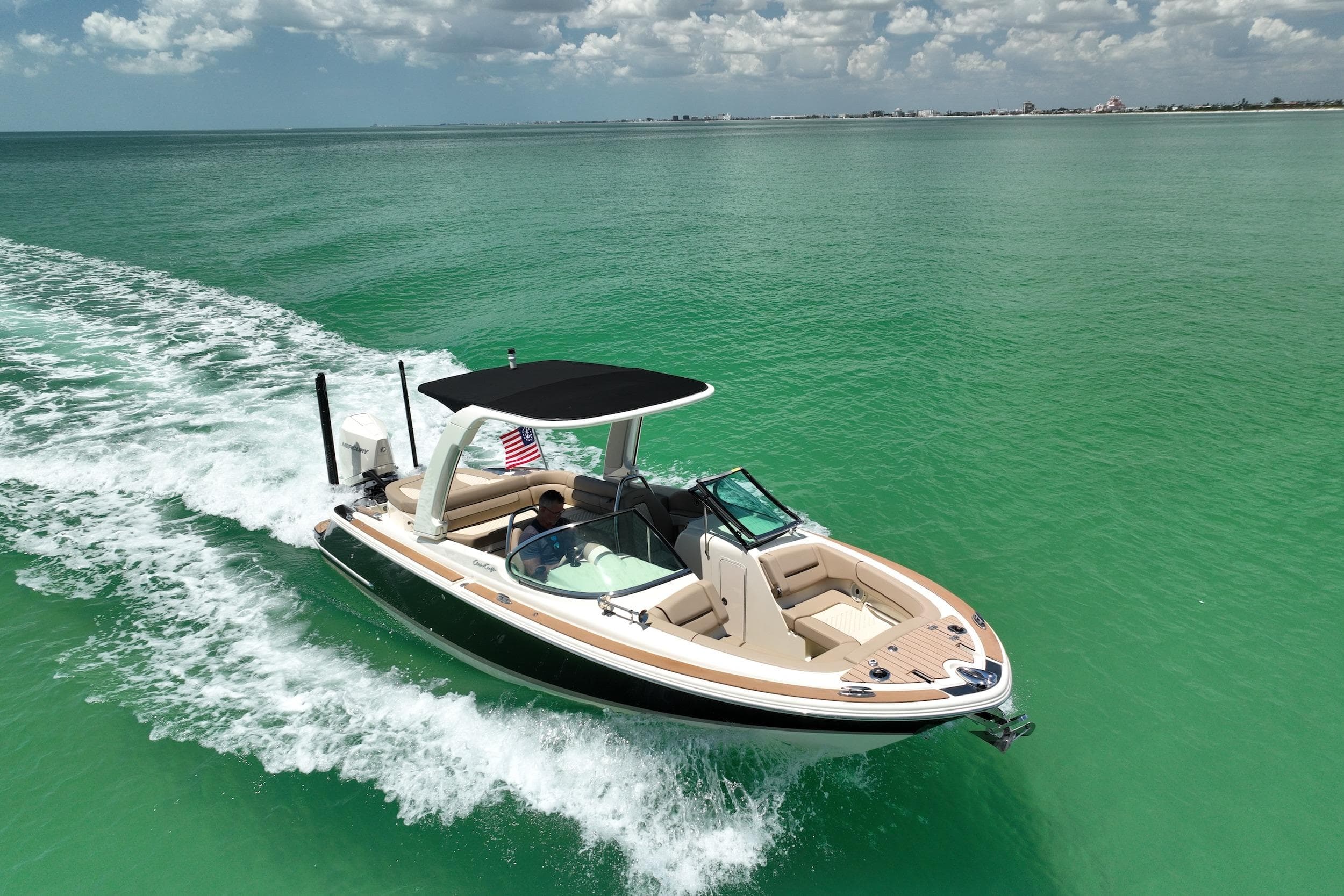 2023 Chris-Craft Launch 25 GT cruising on turquoise waters under a partly cloudy sky.