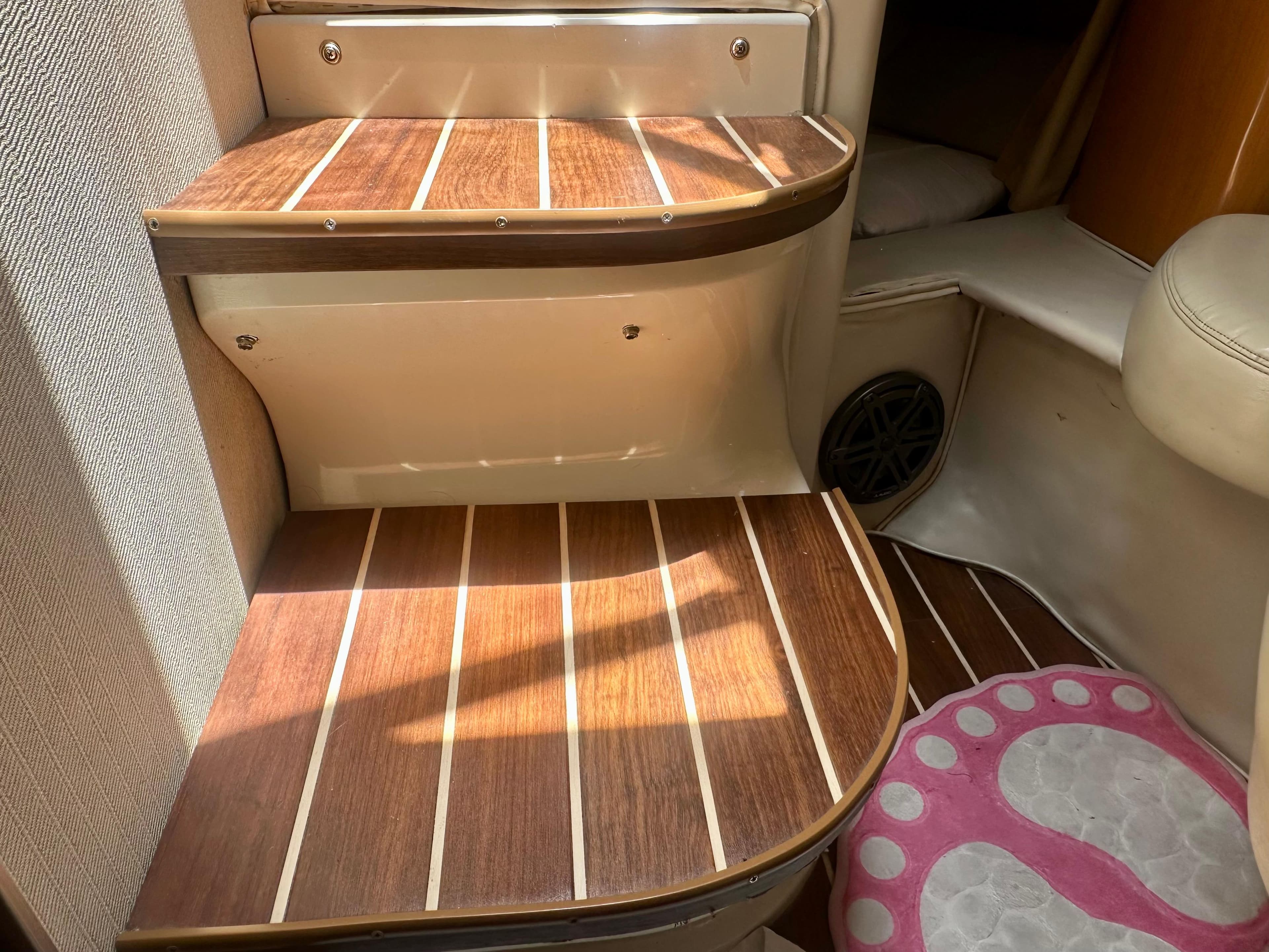 Wooden steps inside 2001 Regal Commodore 2760 boat, featuring striped design and pink foot-shaped mat.