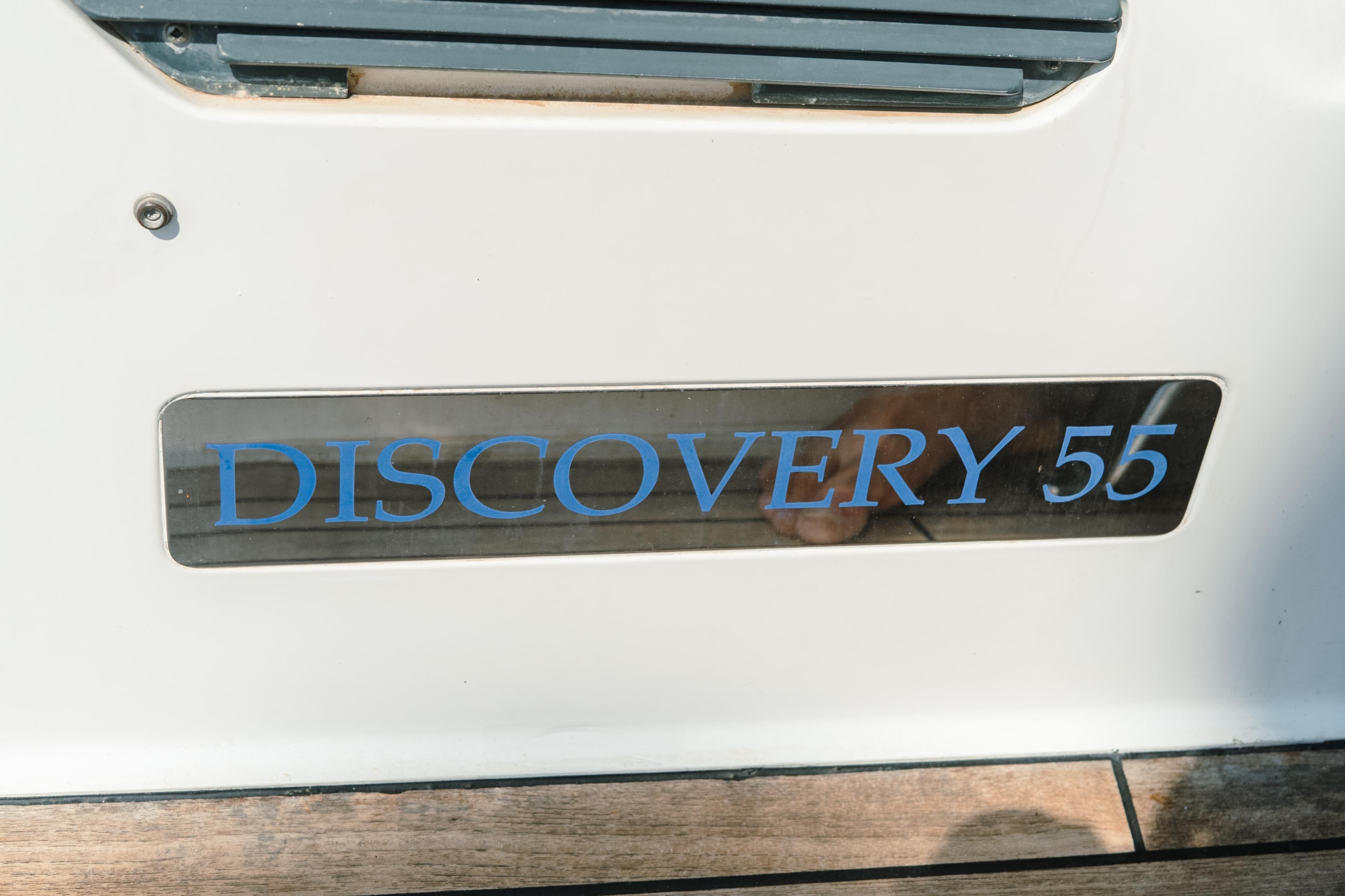 Discovery 55 yacht nameplate, 2004 model, displayed on a white surface.