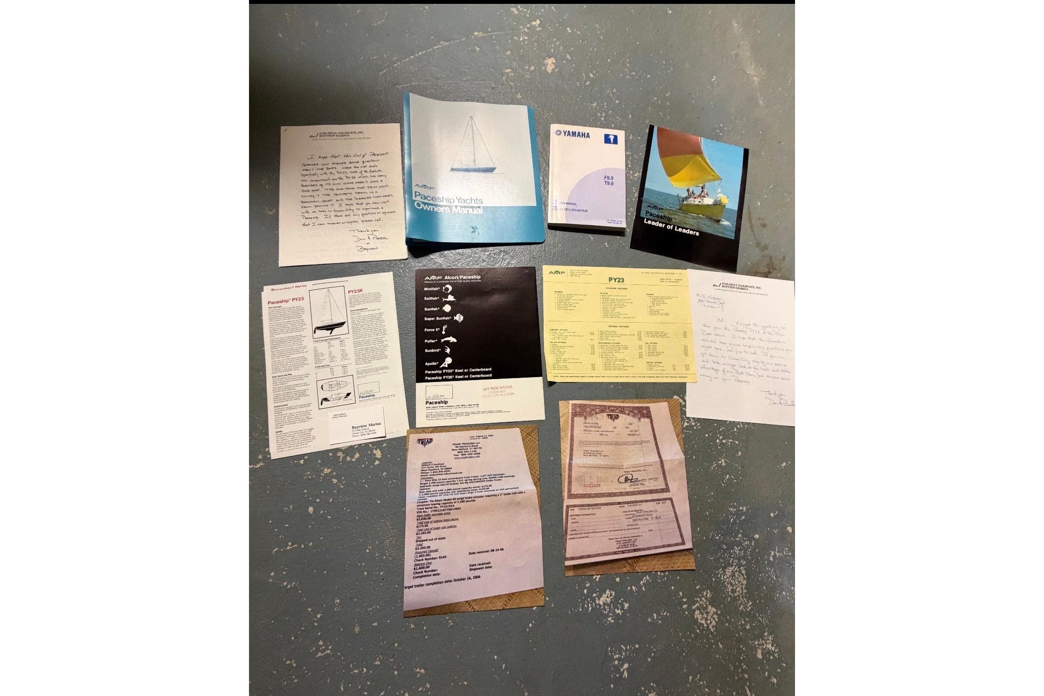 Assorted 1976 PAC 23 yacht manuals and documents displayed on a textured surface.