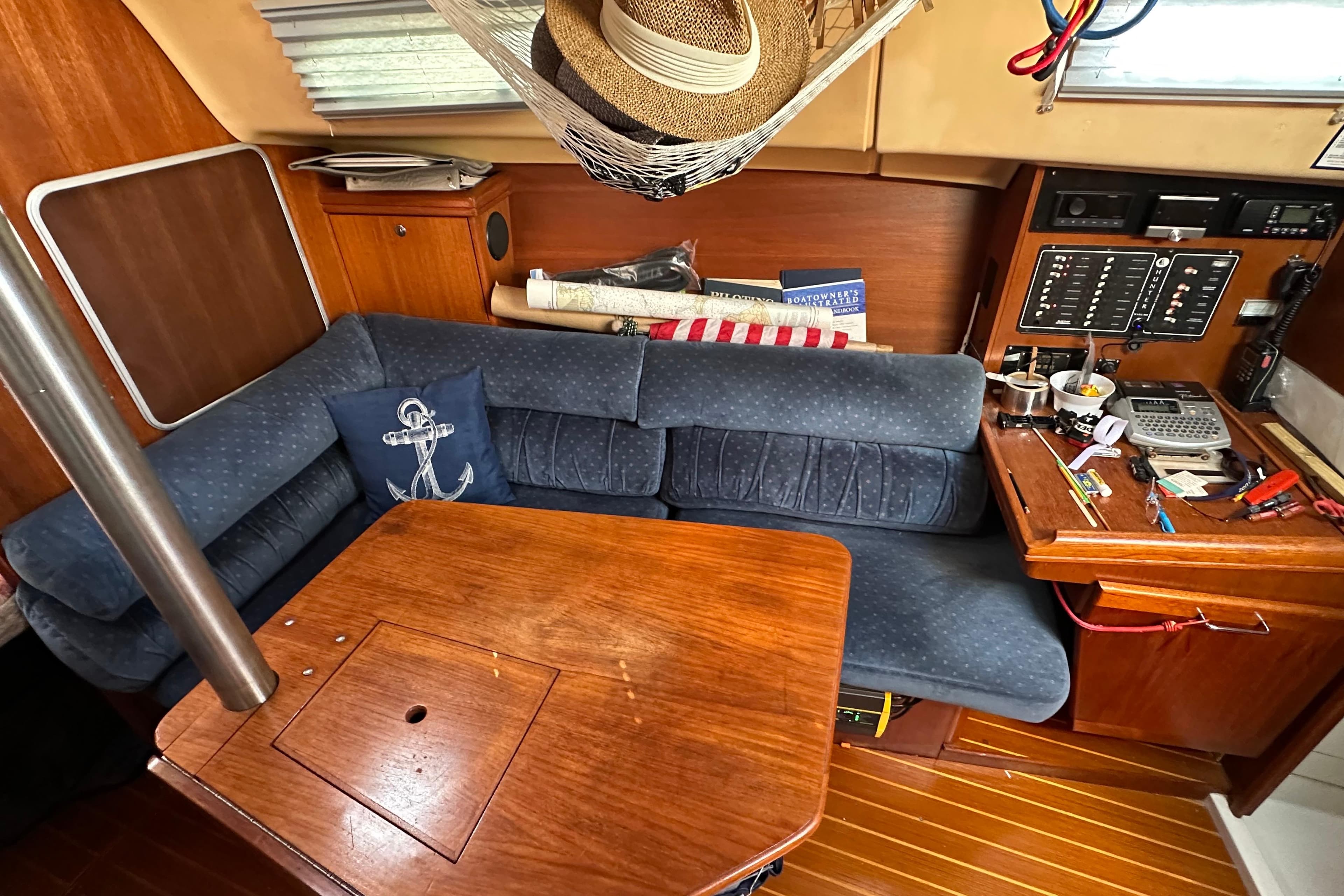 Interior of a 2002 Hunter 306 sailboat with blue seating and wooden table.