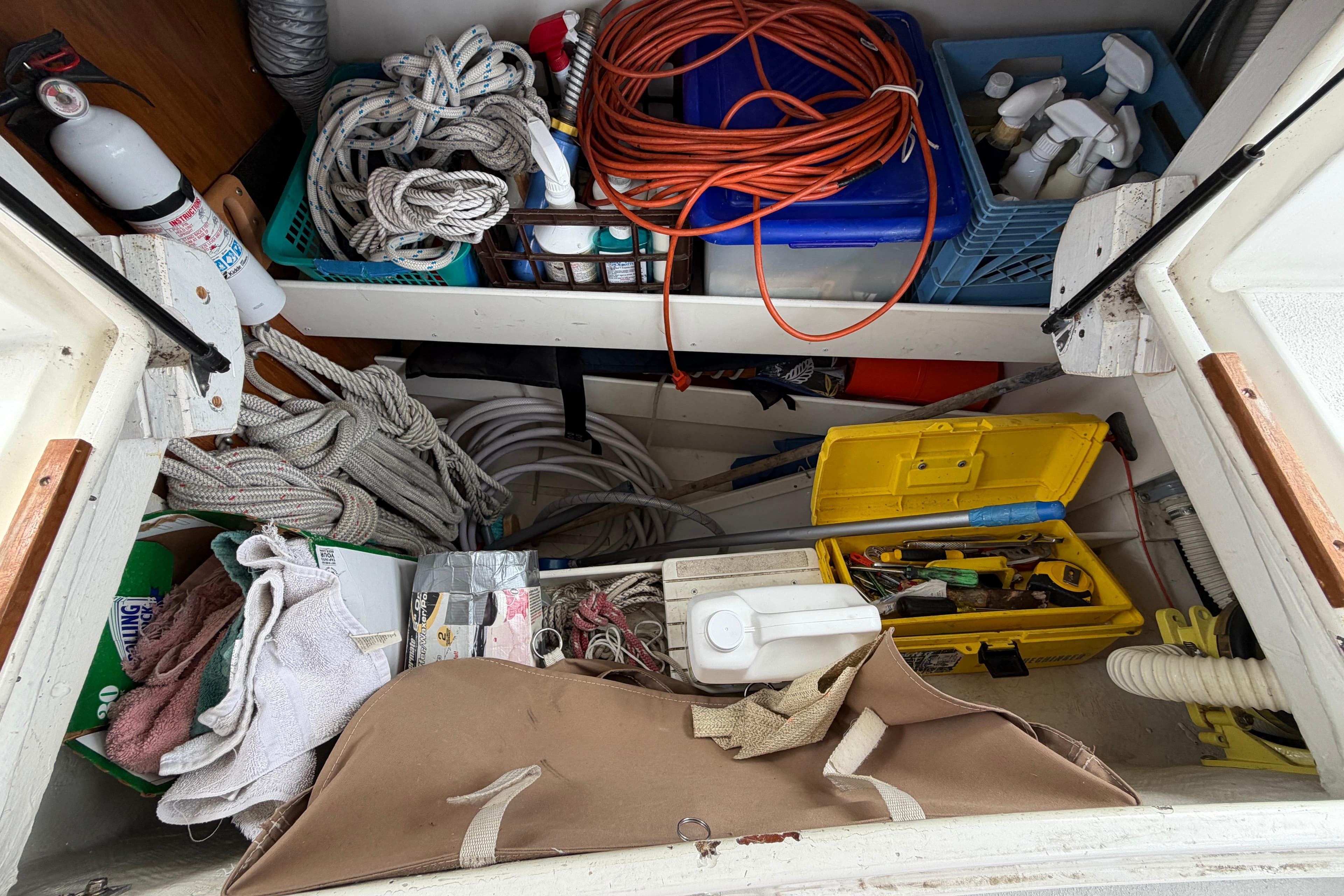 Storage compartment on a 2004 Catalina 350 sailboat with ropes, tools, and cleaning supplies.