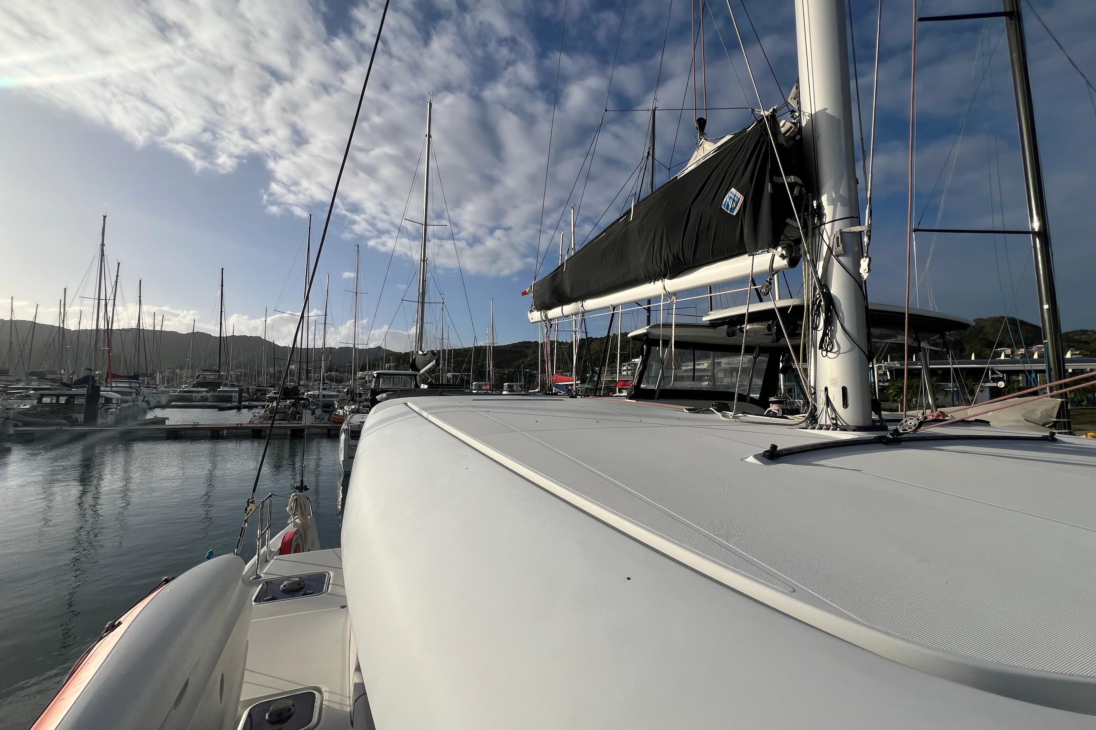 2018 Lagoon 42 catamaran docked in a marina under a partly cloudy sky.