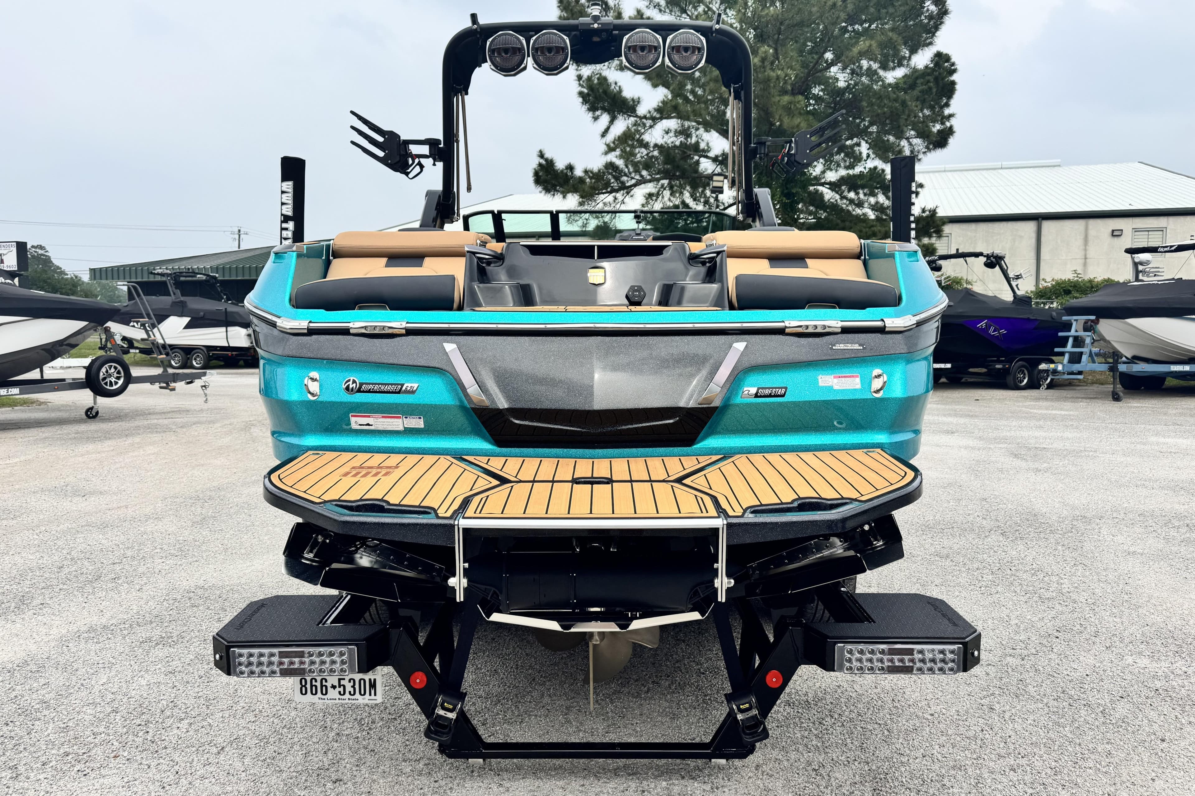 2025 MasterCraft X26 boat, rear view, teal color, parked outdoors.