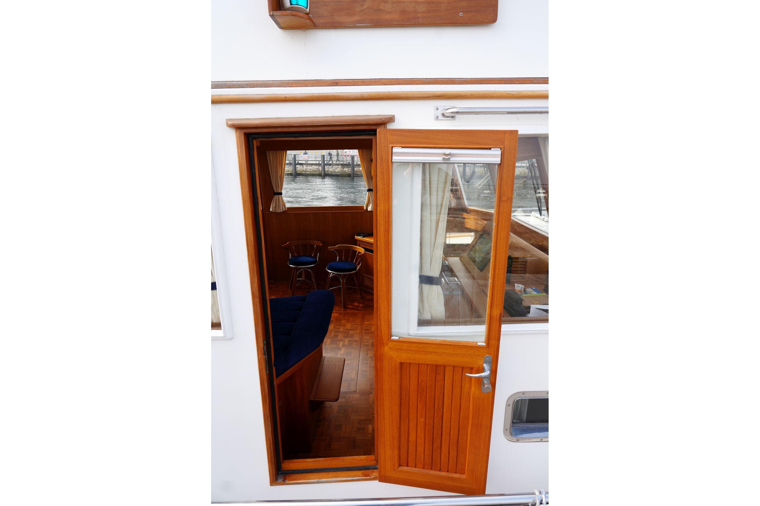 Wooden door entrance to 1997 Grand Banks 46 Motoryacht, revealing interior seating area.