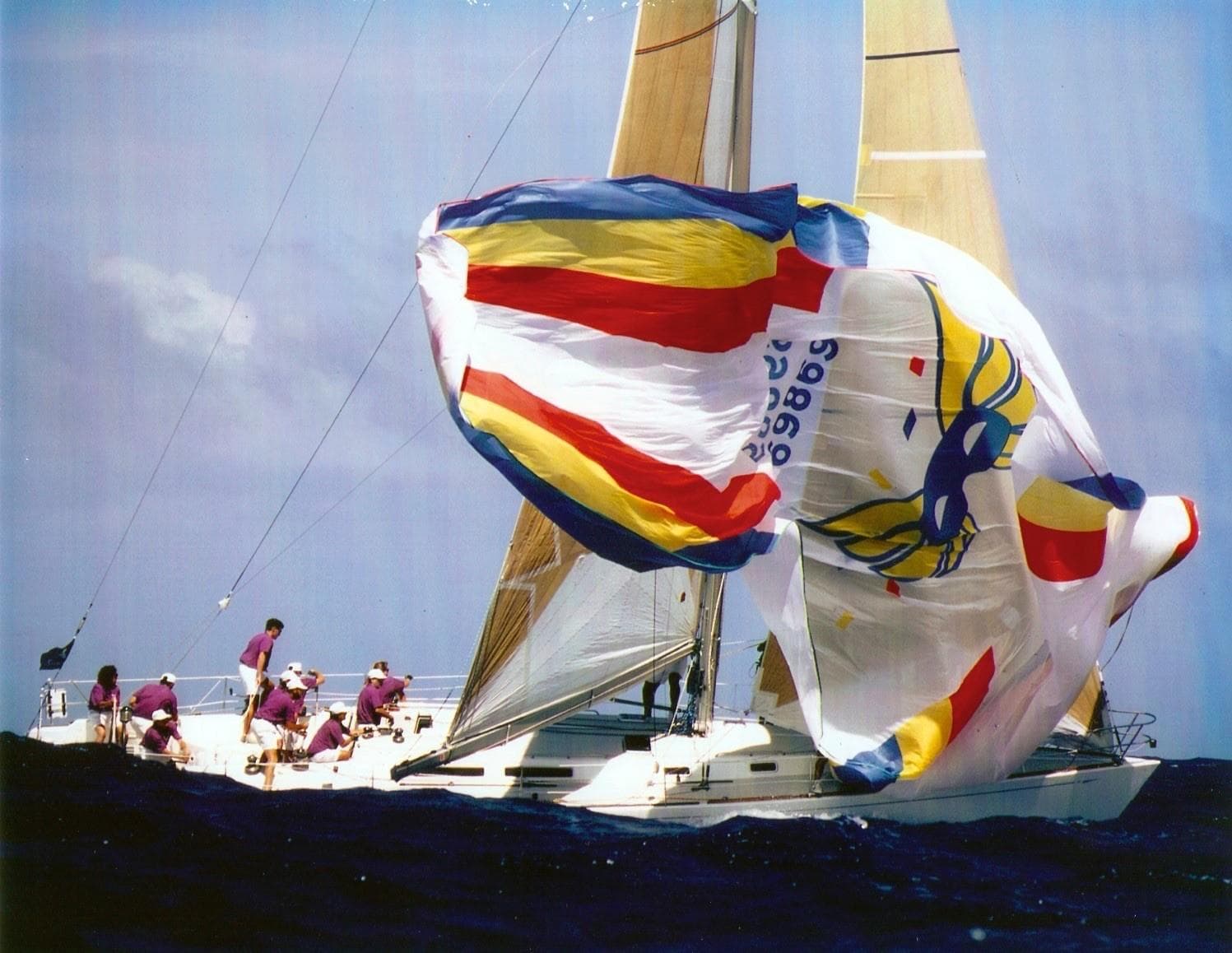 Sailing yacht Santa Cruz 52, 1993, with colorful spinnaker and crew on deck.