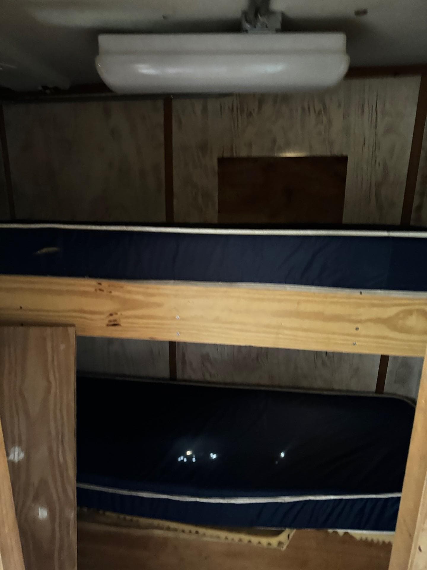 Interior of 1971 Butterfish Fishing Trawler with wooden bunk beds and overhead light.