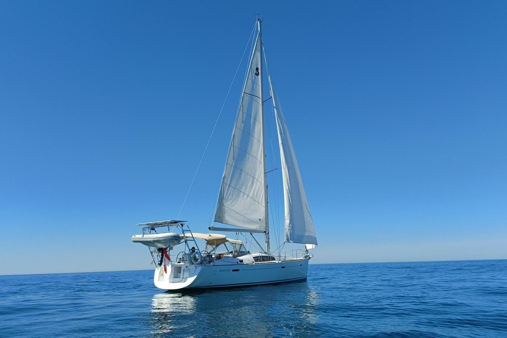 2009 Beneteau 43 sailboat on calm blue sea under clear sky.