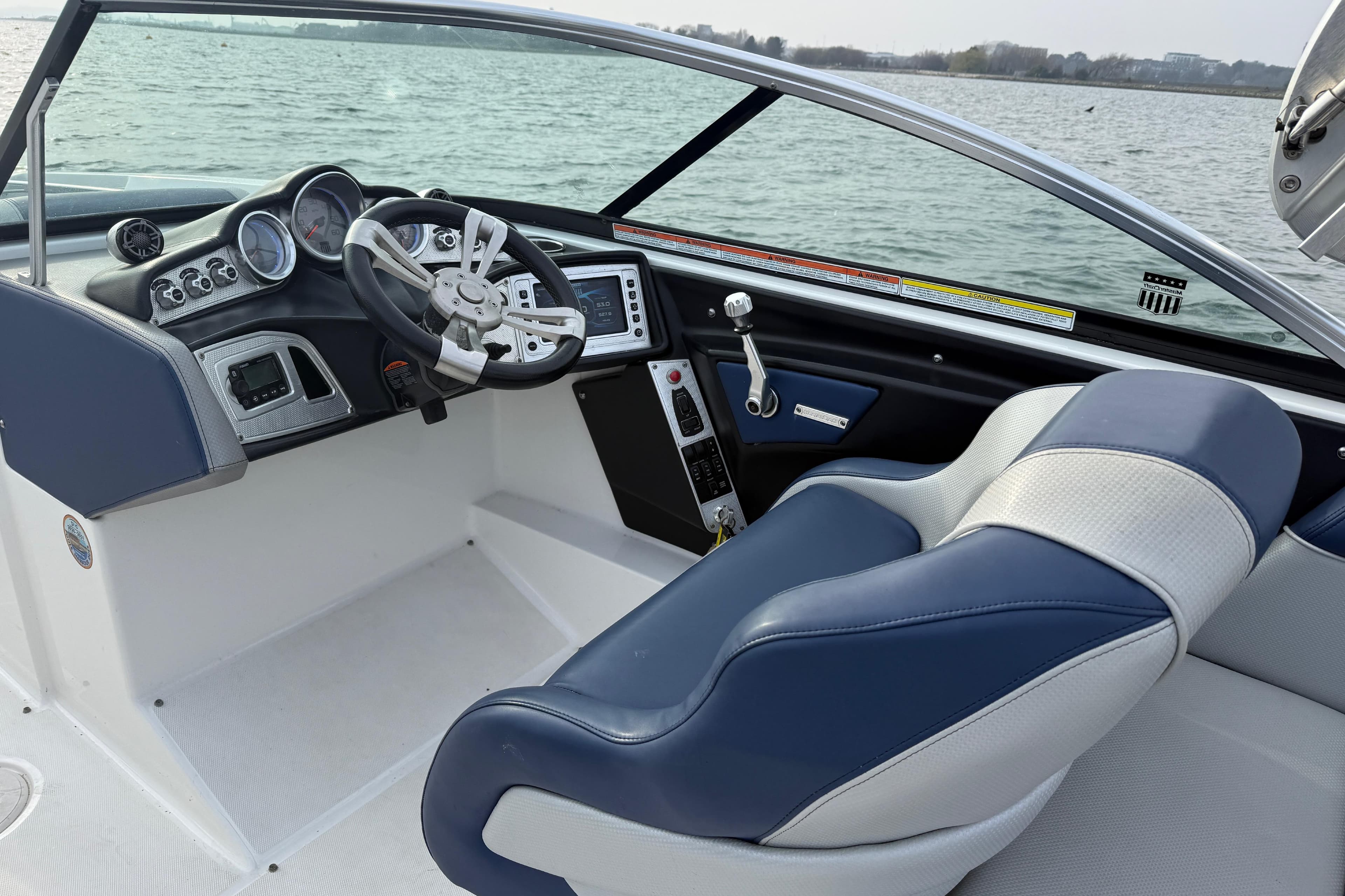 2015 MasterCraft X46 boat interior with steering wheel and dashboard, overlooking water.