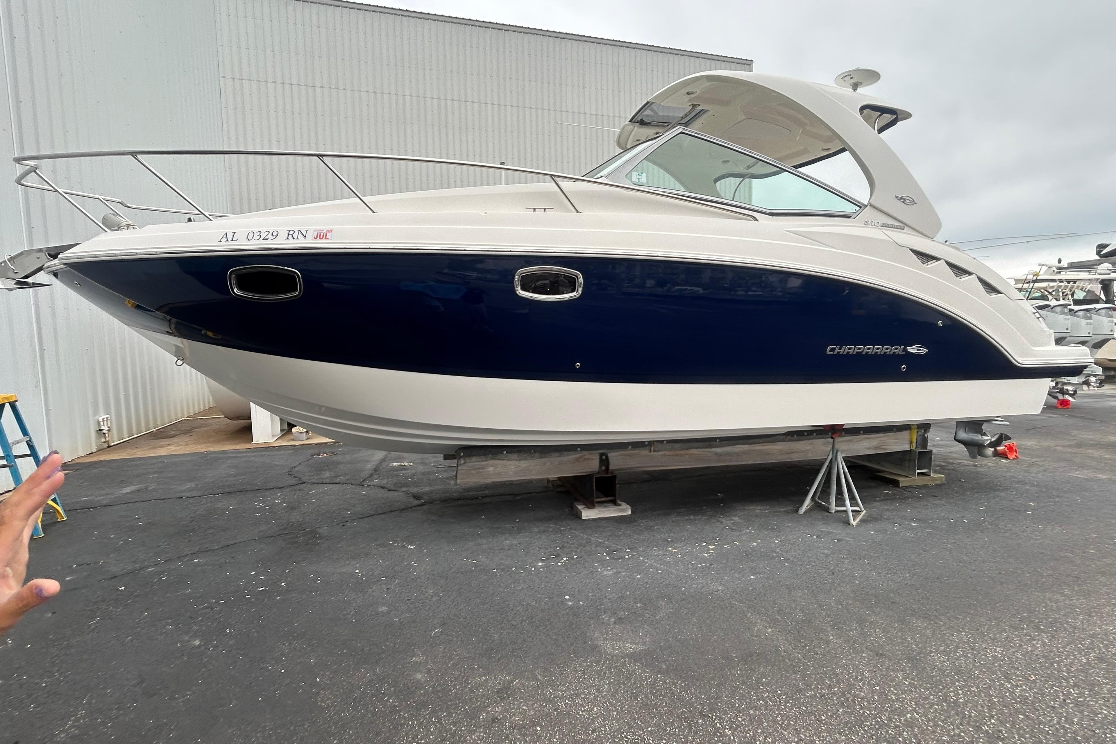 2014 Chaparral 310 Signature boat on stands, blue and white hull, dockside view.