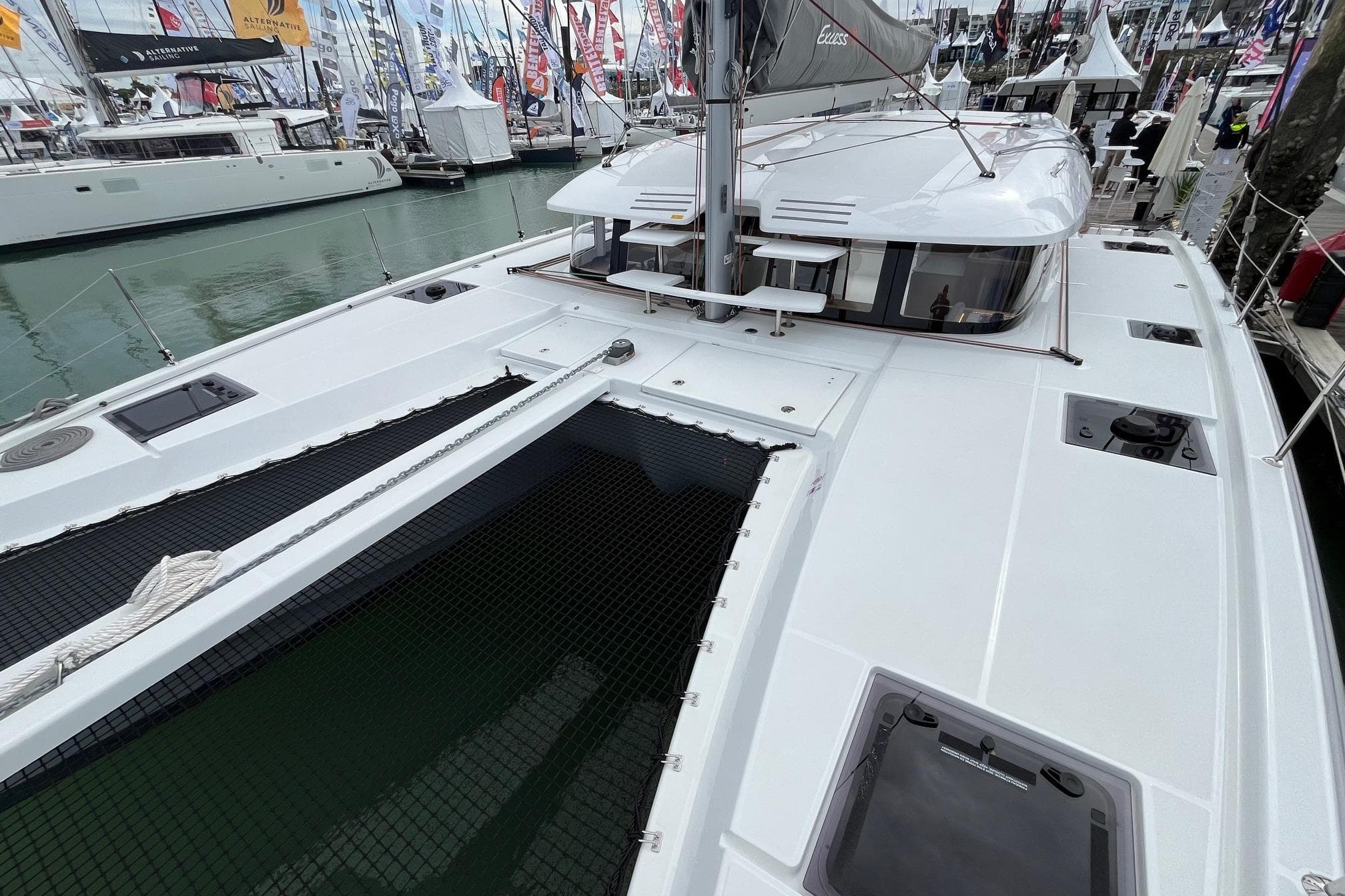 2025 Excess EXCESS 11 catamaran at a boat show, showcasing sleek design and spacious deck.